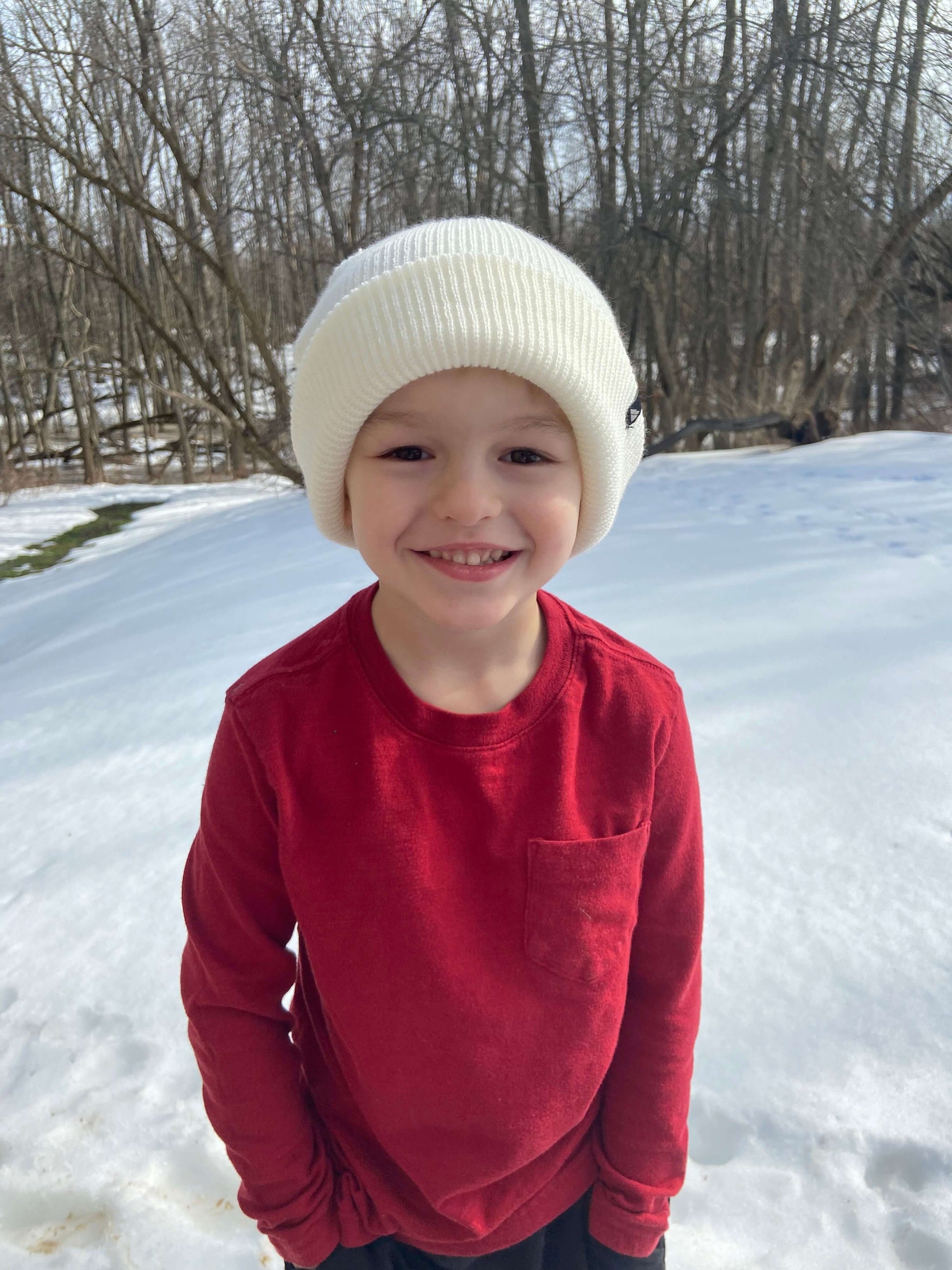 Child Acrylic Cuff Hat – Soft Knit Beanie for Kids worn by a smiling child in snow during winter.