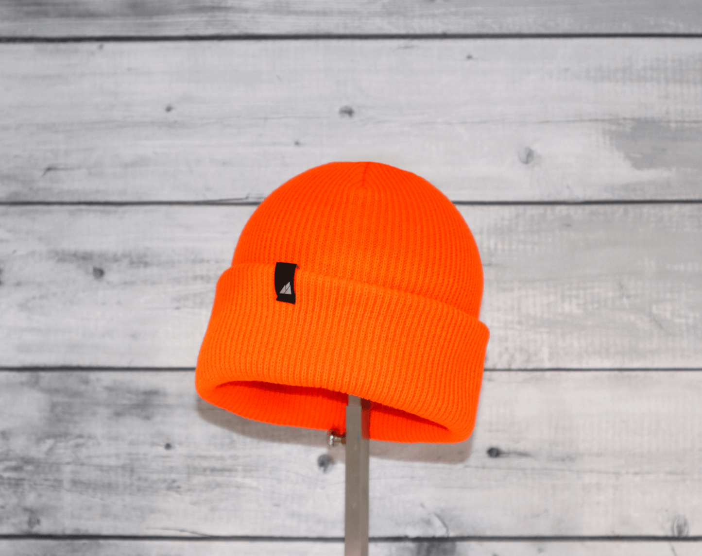 Child Acrylic Cuff Hat – Soft Knit Beanie for Kids in bright orange color displayed on a stand.