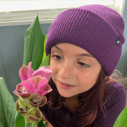 Child Acrylic Cuff Hat – Soft Knit Beanie for Kids worn by a girl near a flower, showcasing warmth and comfort.