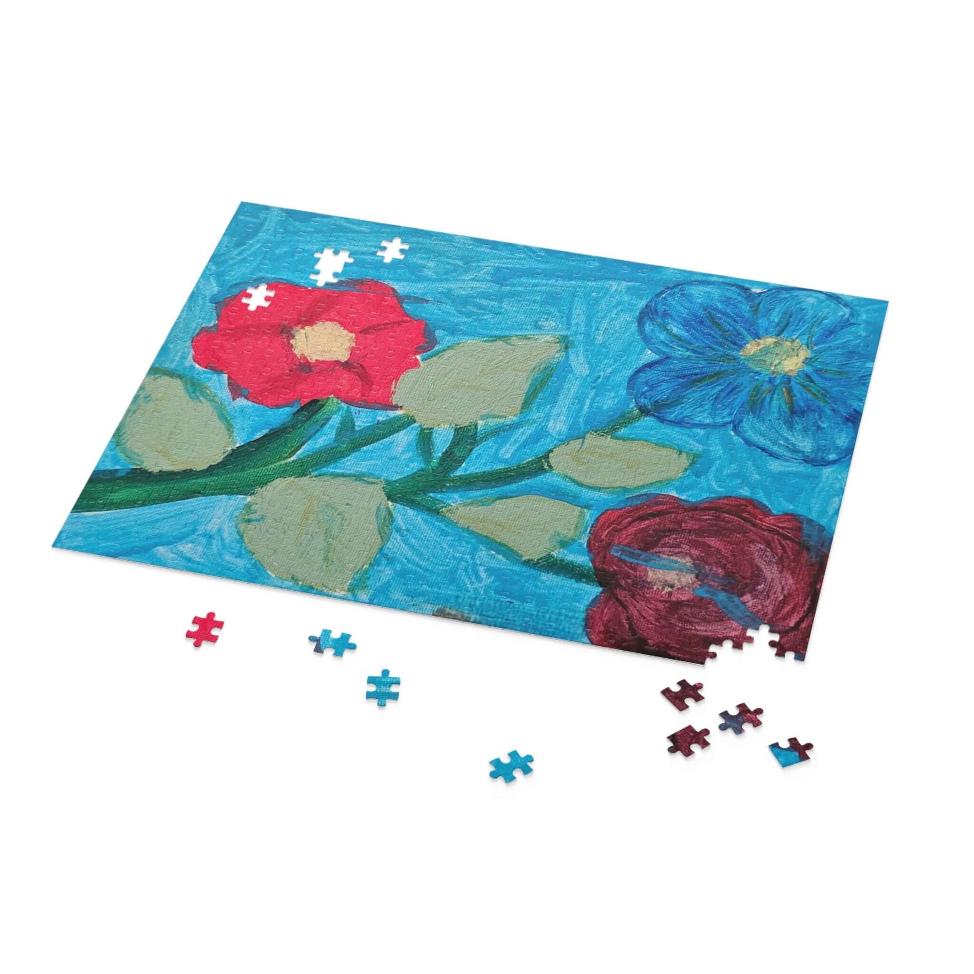 Colorful flower puzzle pieces scattered next to a vibrant blue floral puzzle awaiting completion.