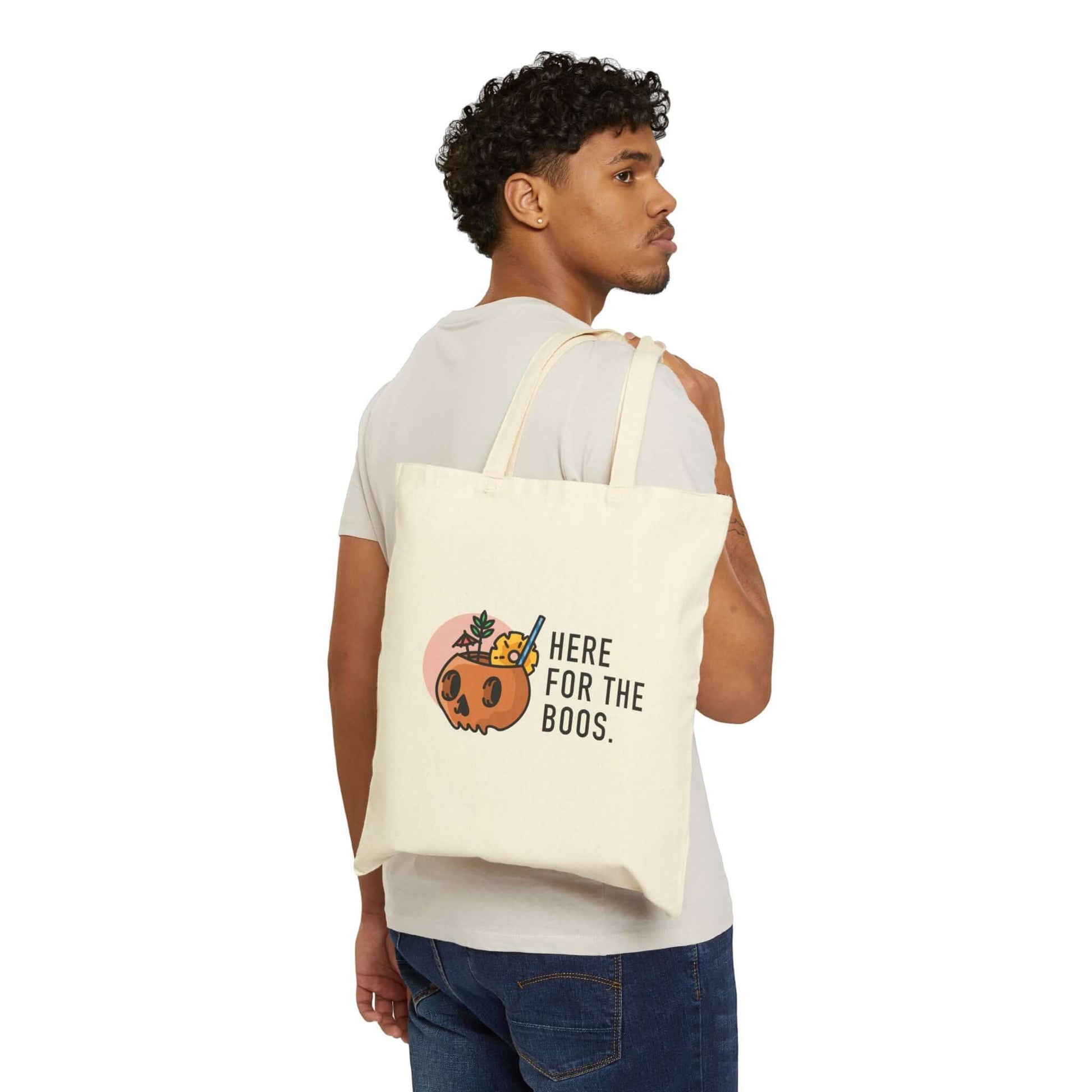 Man holding a Double-Sided Halloween Tote – “Here for the Boos” + Spooky Vibes with pumpkin cocktail design.