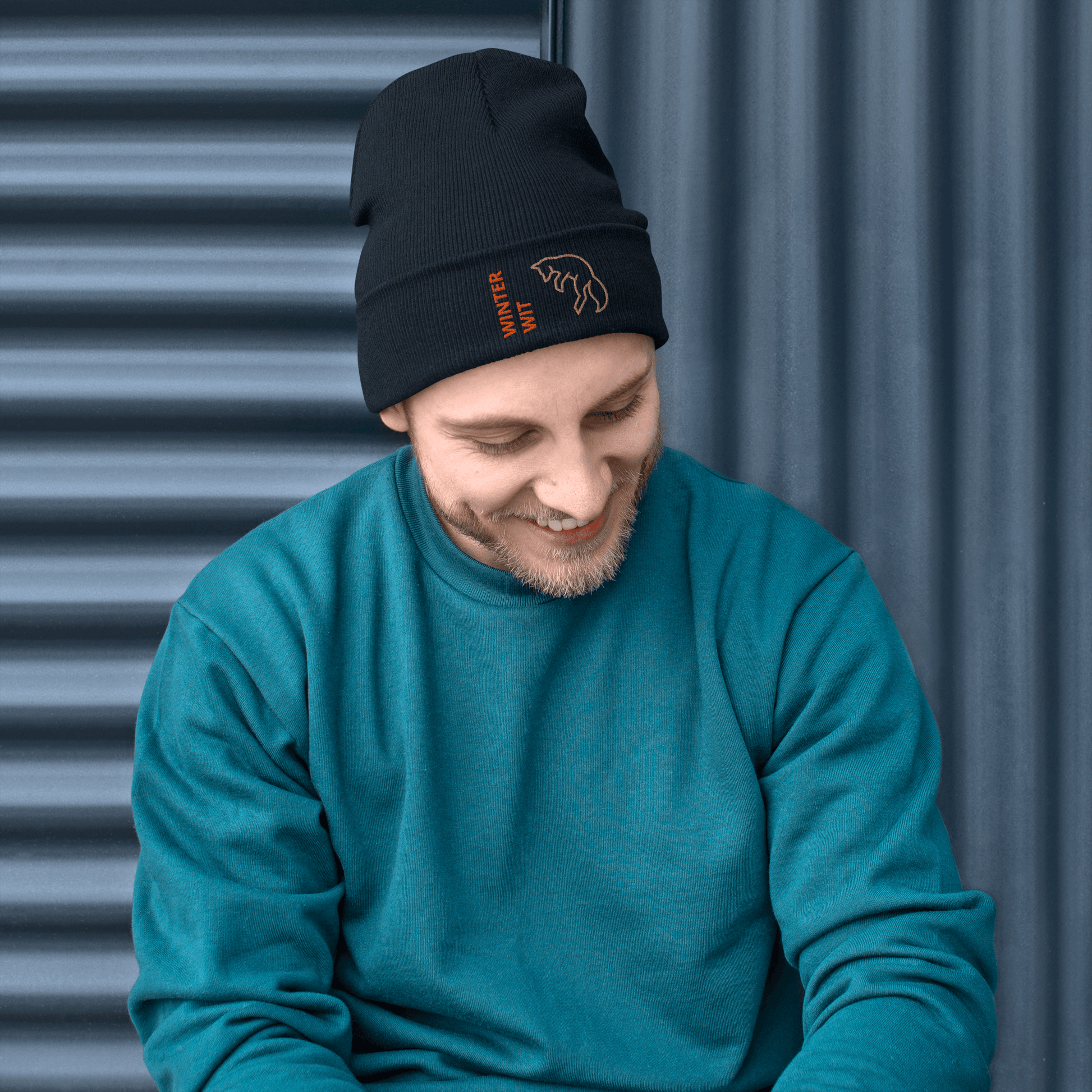 Man wearing a stylish Fox Beanie – Embroidered Knit Hat with Custom Text, smiling against a textured background.