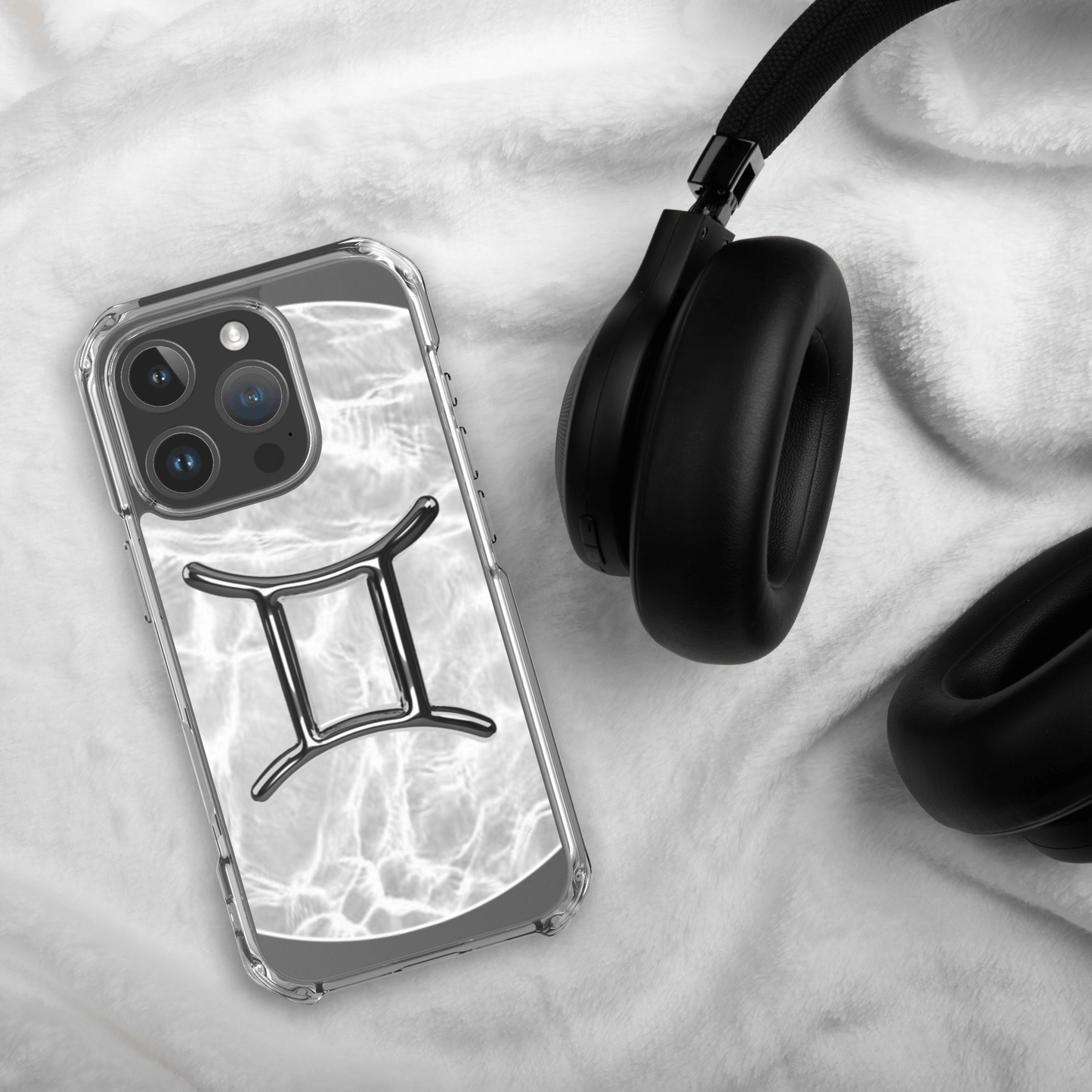 Zodiac Gemini Magsafe clear iPhone case with marble design, resting on a soft surface next to black headphones.