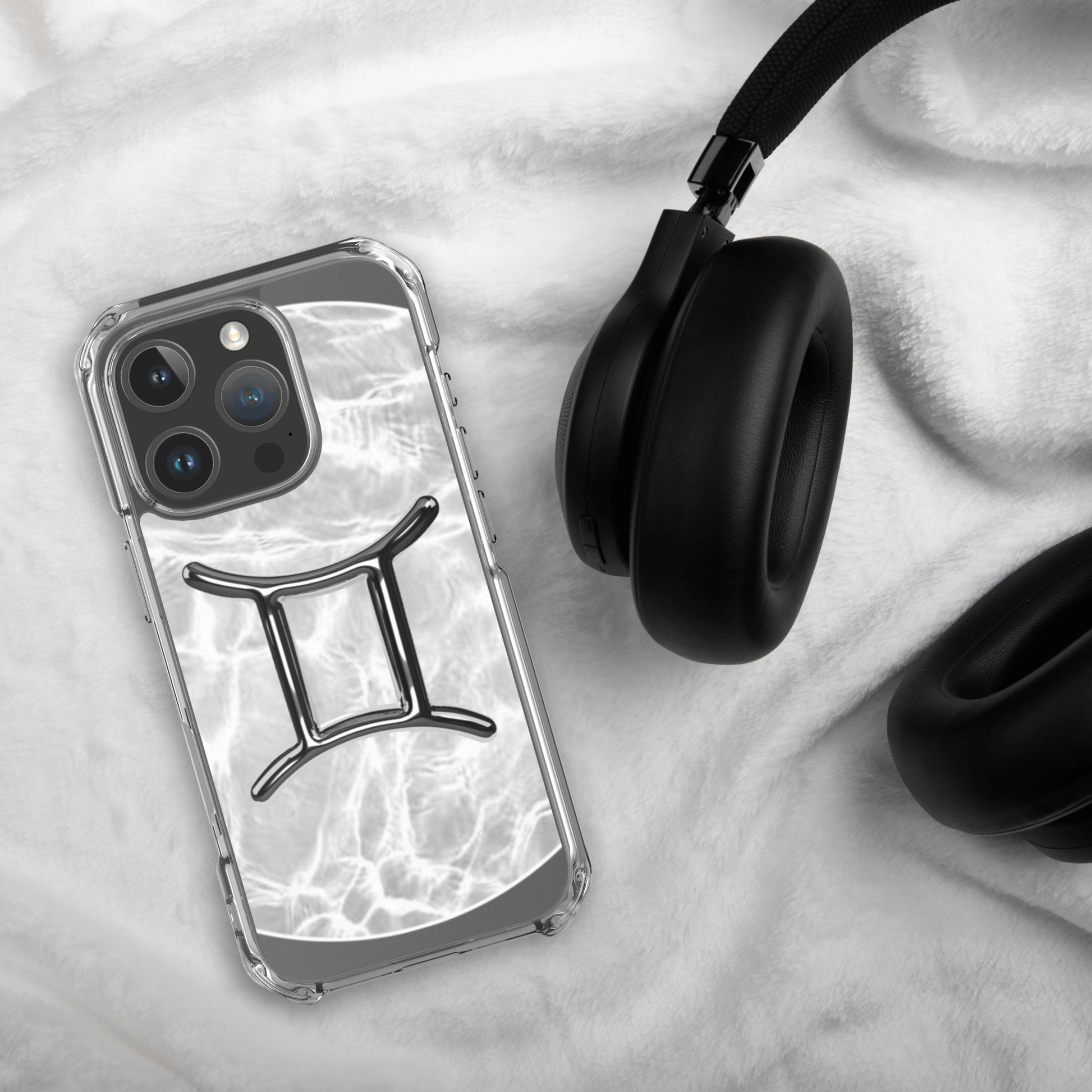 Zodiac Gemini Magsafe clear iPhone case with marble design, resting on a soft surface next to black headphones.