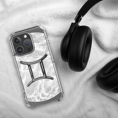 Zodiac Gemini Magsafe clear iPhone case with marble design, resting on a soft surface next to black headphones.