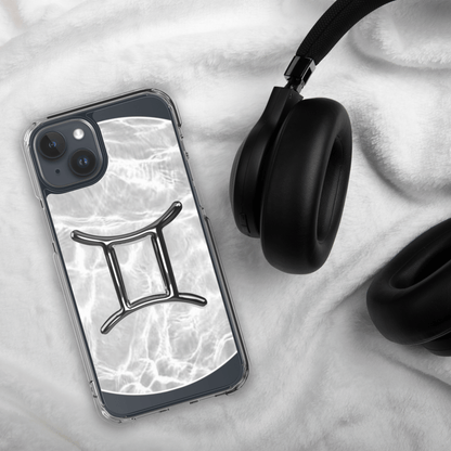 Clear iPhone case featuring Gemini zodiac design on a marble backdrop, paired with stylish headphones.