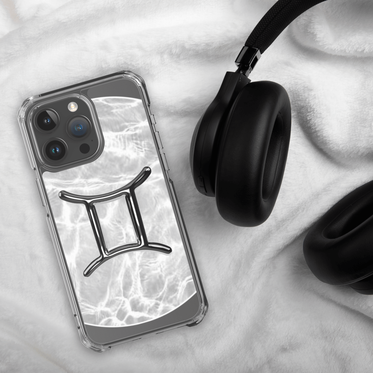 Zodiac Gemini Magsafe clear iPhone case with metallic design on a cozy surface next to headphones.