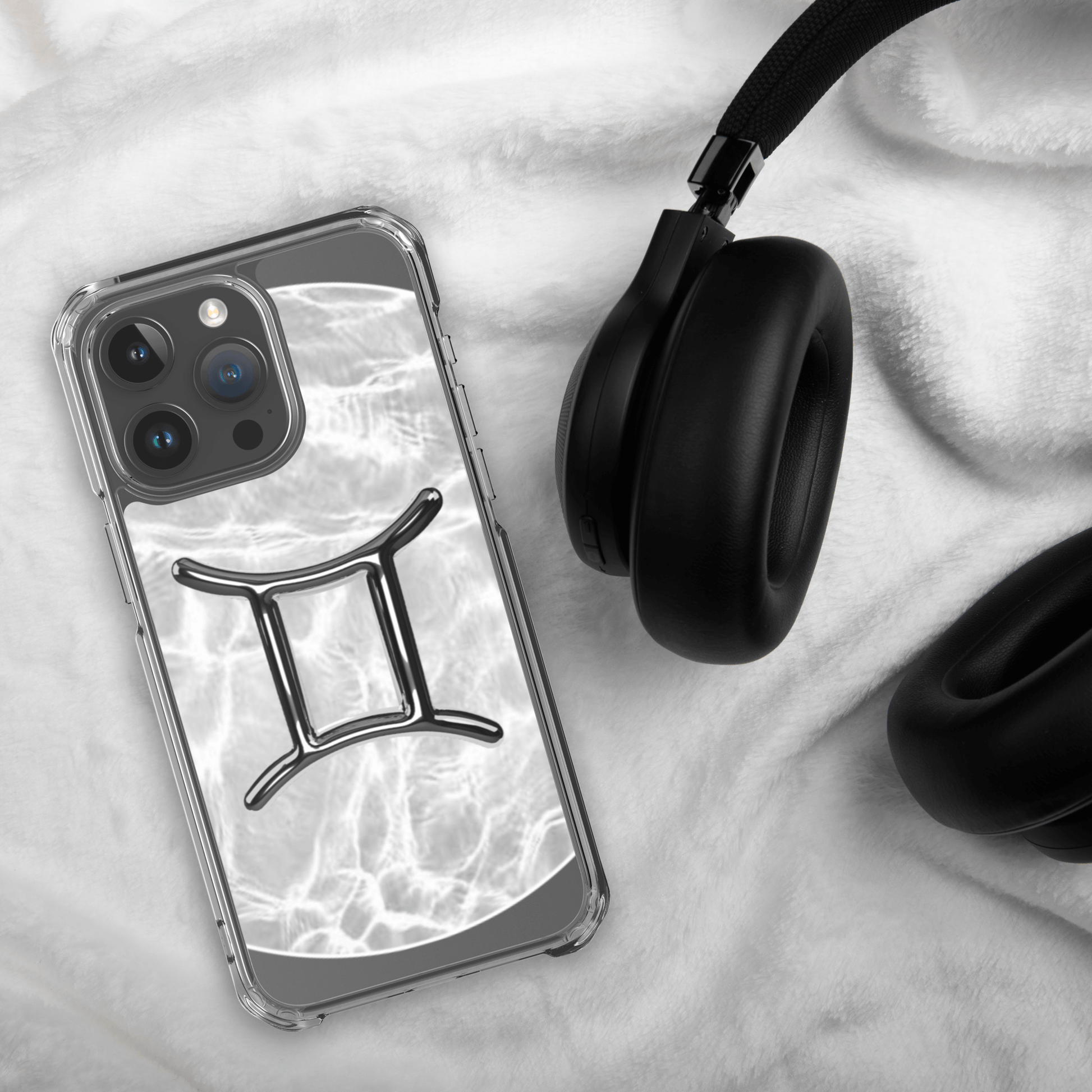 Zodiac Gemini Magsafe clear iPhone case with metallic design on a cozy surface next to headphones.