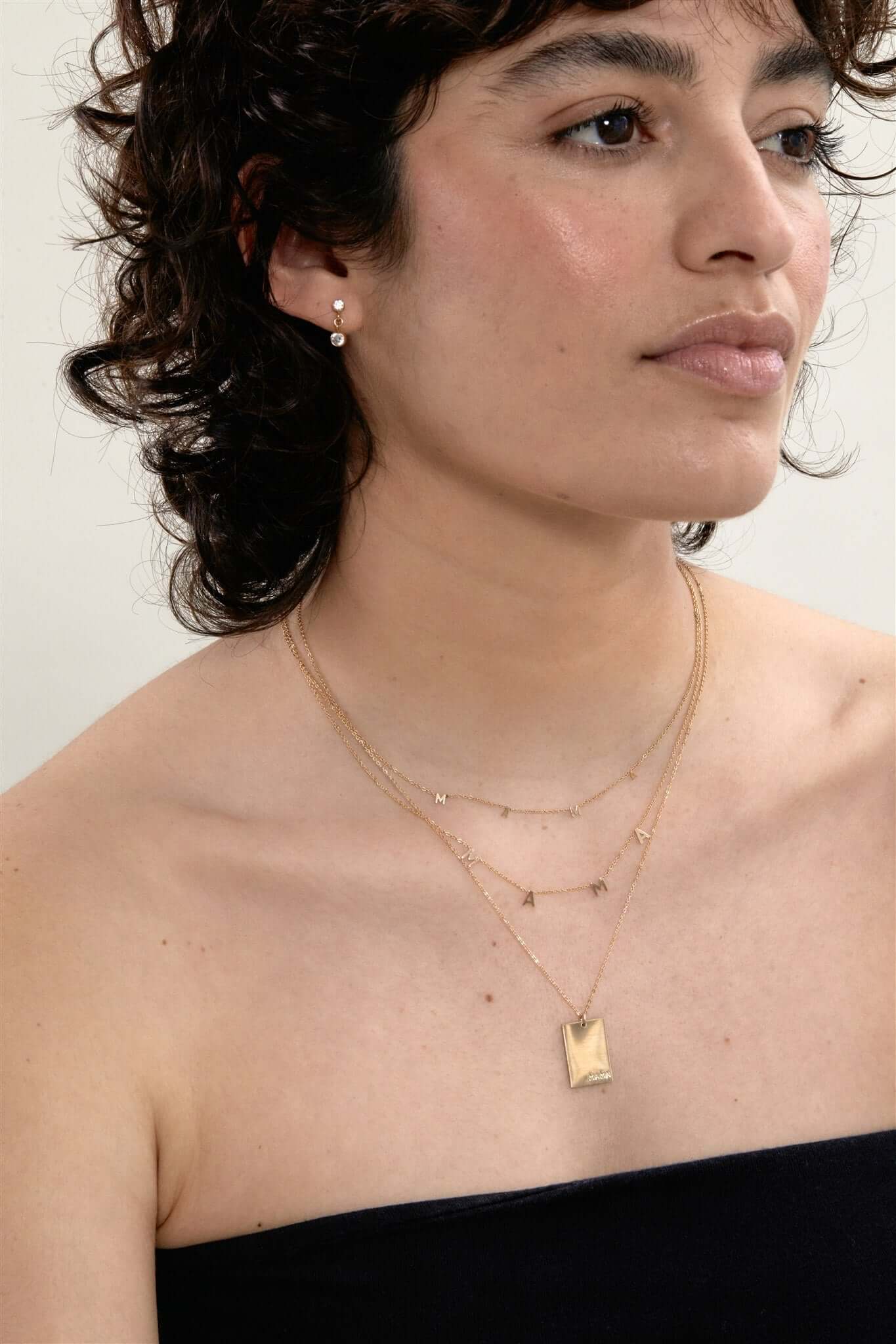 Goldie MAMA Necklace – Hand-Stamped 14k Gold-Filled Pendant worn by model, showcasing layered gold necklaces.