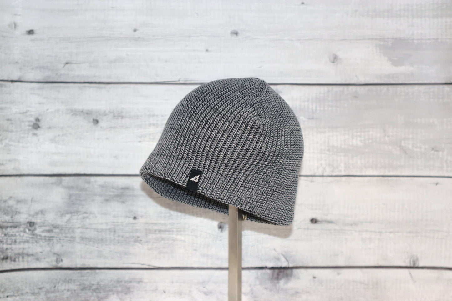 Infant Acrylic Cuff Hat – Soft Knit Beanie for Ages 3–12M displayed on a stand against a rustic wood background.
