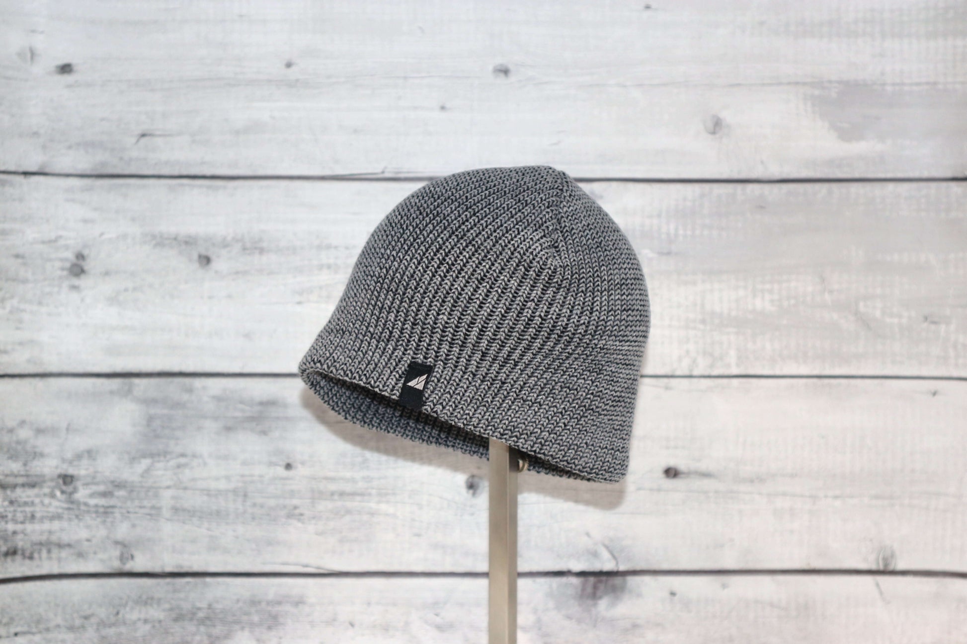 Infant Acrylic Cuff Hat – Soft Knit Beanie for Ages 3–12M displayed on a stand against a rustic wood background.