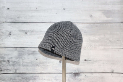 Infant Acrylic Cuff Hat – Soft Knit Beanie for Ages 3–12M displayed on a stand against a rustic wood background.