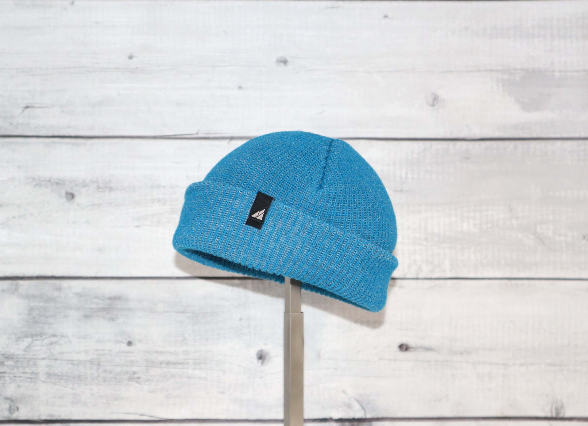 Infant Acrylic Cuff Hat – Soft Knit Beanie for Ages 3–12M in blue on a wooden background.