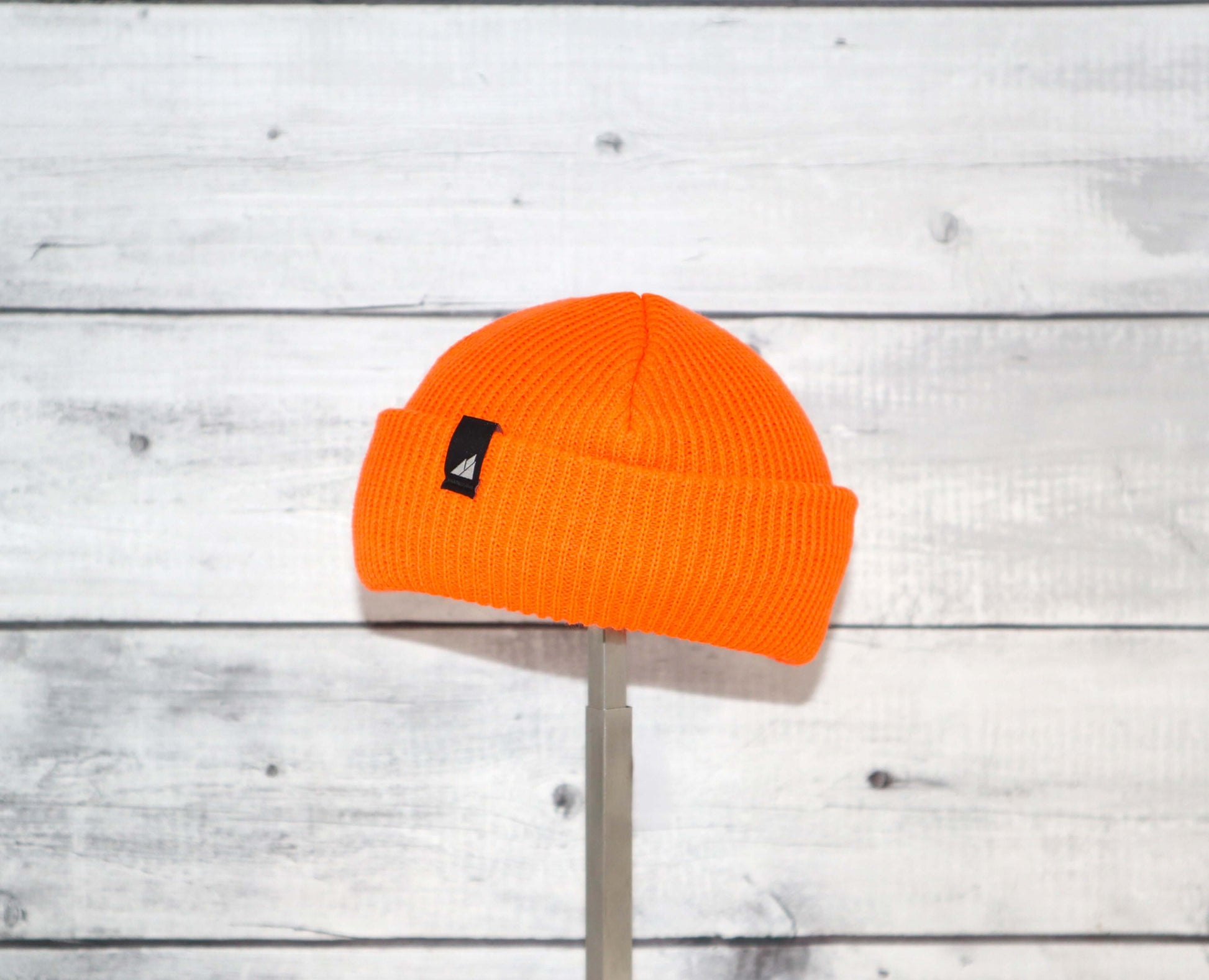 Infant Acrylic Cuff Hat – Soft Knit Beanie for Ages 3–12M in bright orange color displayed on a wooden background.