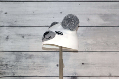 Infant Specialty Hat – Cozy, Playful, Purposeful featuring a cute animal design with grey ears and pom poms.