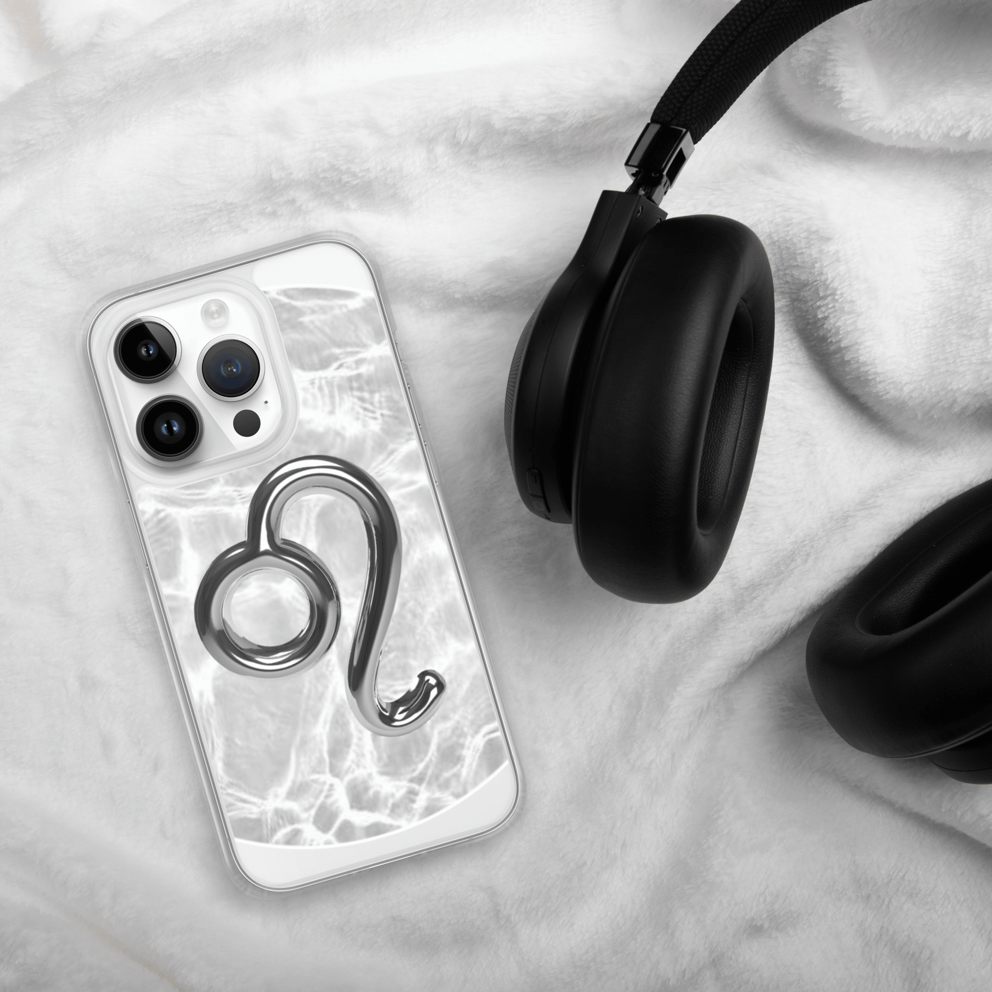 Zodiac Leo Magsafe clear iPhone case with marble design next to stylish headphones on soft fabric.
