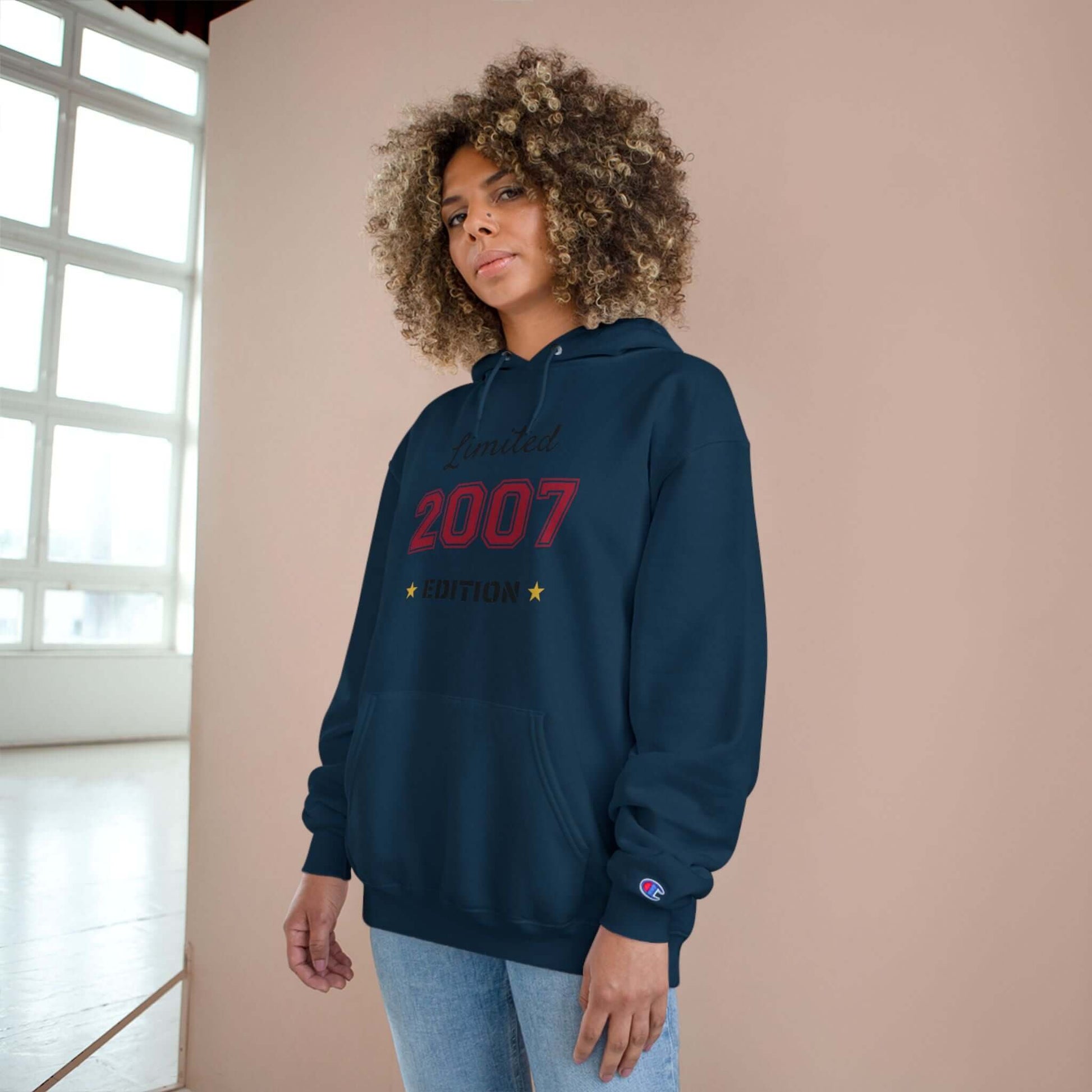 Limited Edition Year Hoodie – Champion Comfort, Collegiate Colors worn by a model with curly hair in a stylish setting.