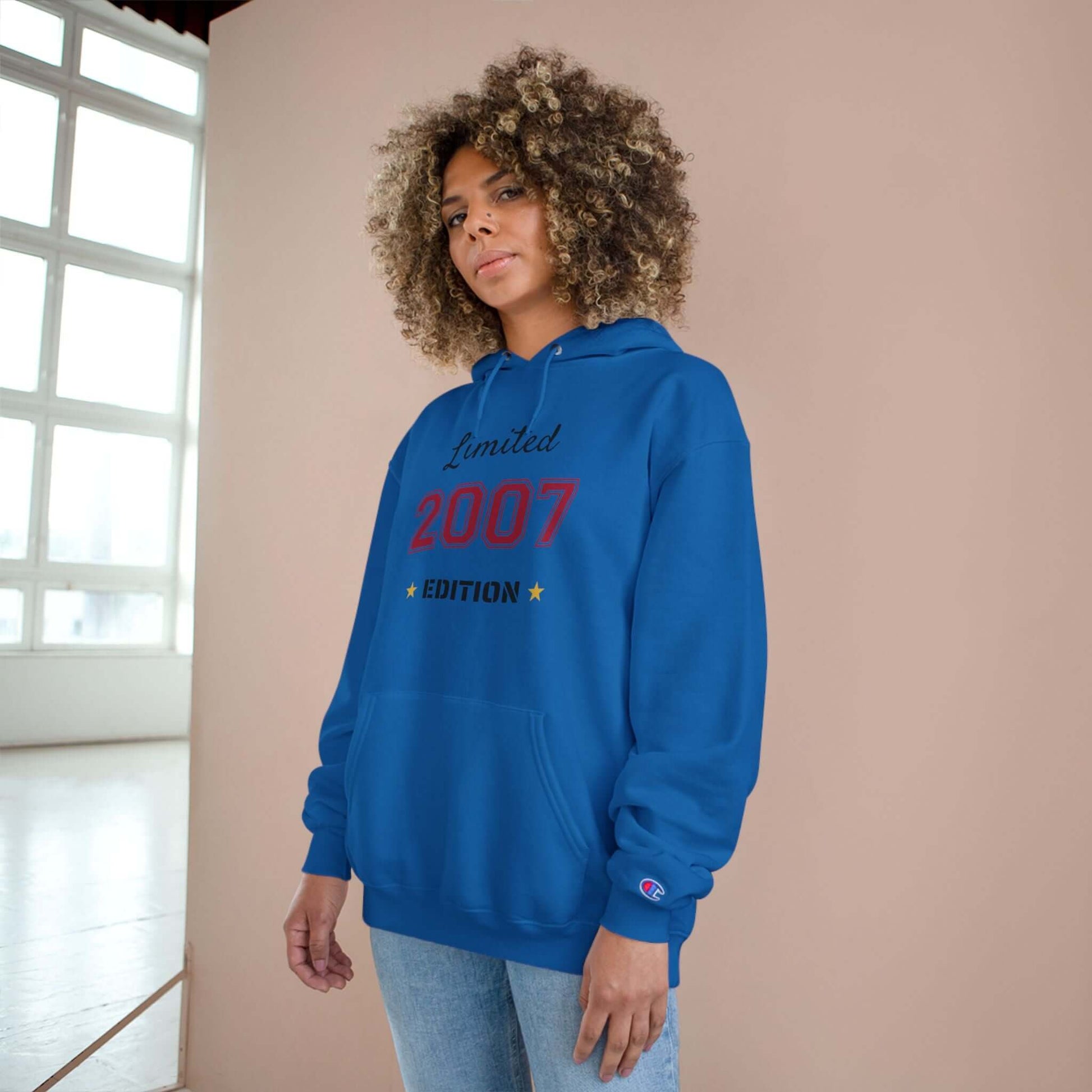 Limited Edition Year Hoodie – Champion Comfort, Collegiate Colors in blue worn by a model with curly hair.
