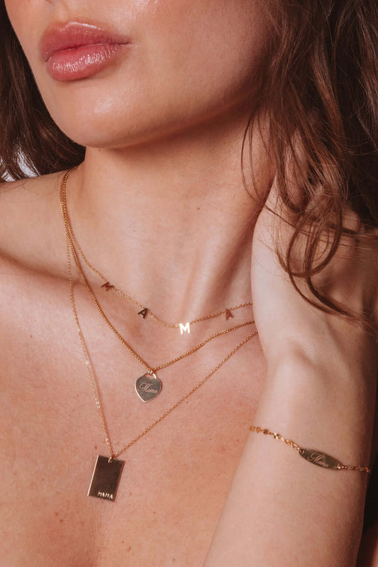 Mama Alice Necklace – 14k Gold-Filled Heart on Wheat Chain worn elegantly with other gold necklaces.