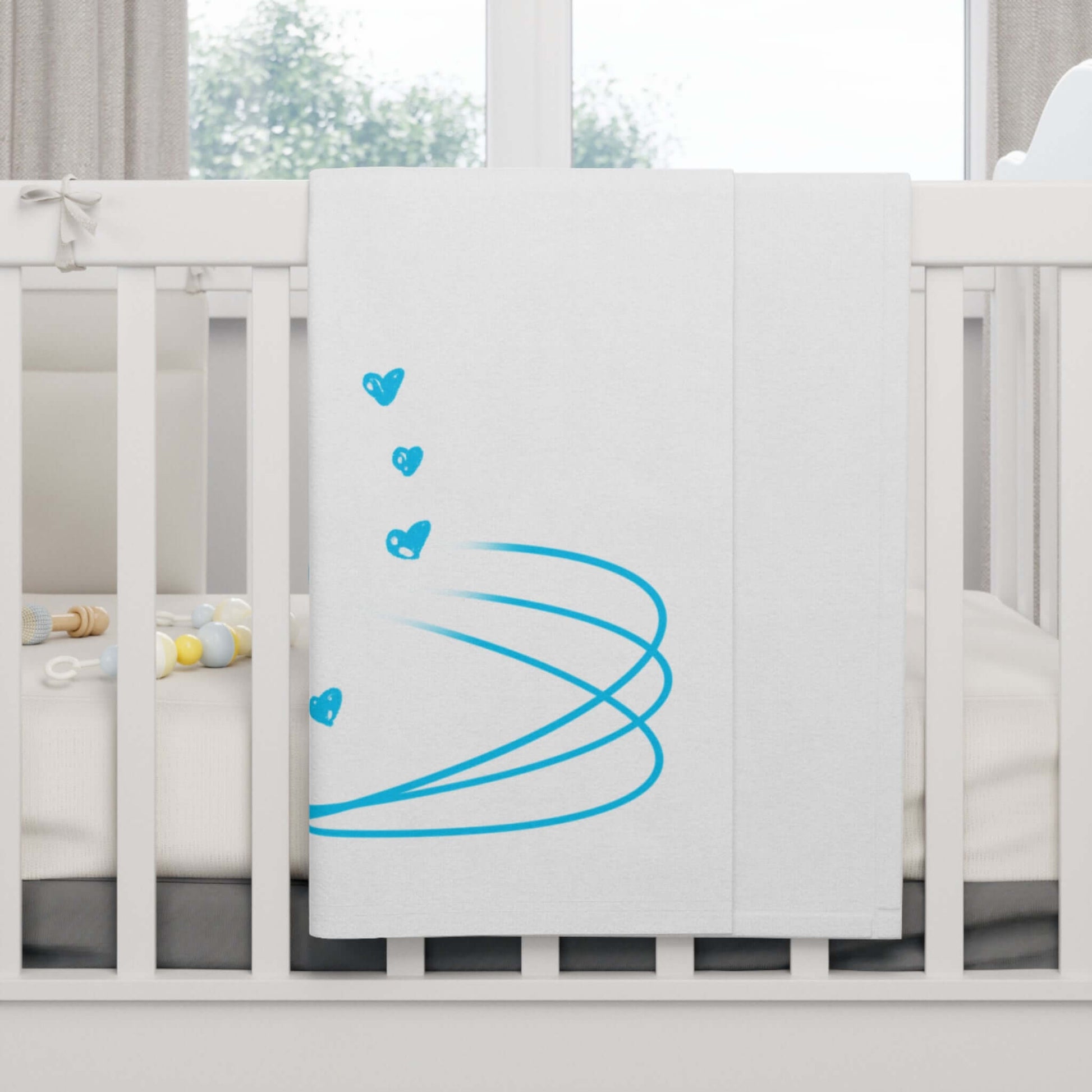 Personalized baby blanket with blue heart design draped over a crib for cozy nursery decor.