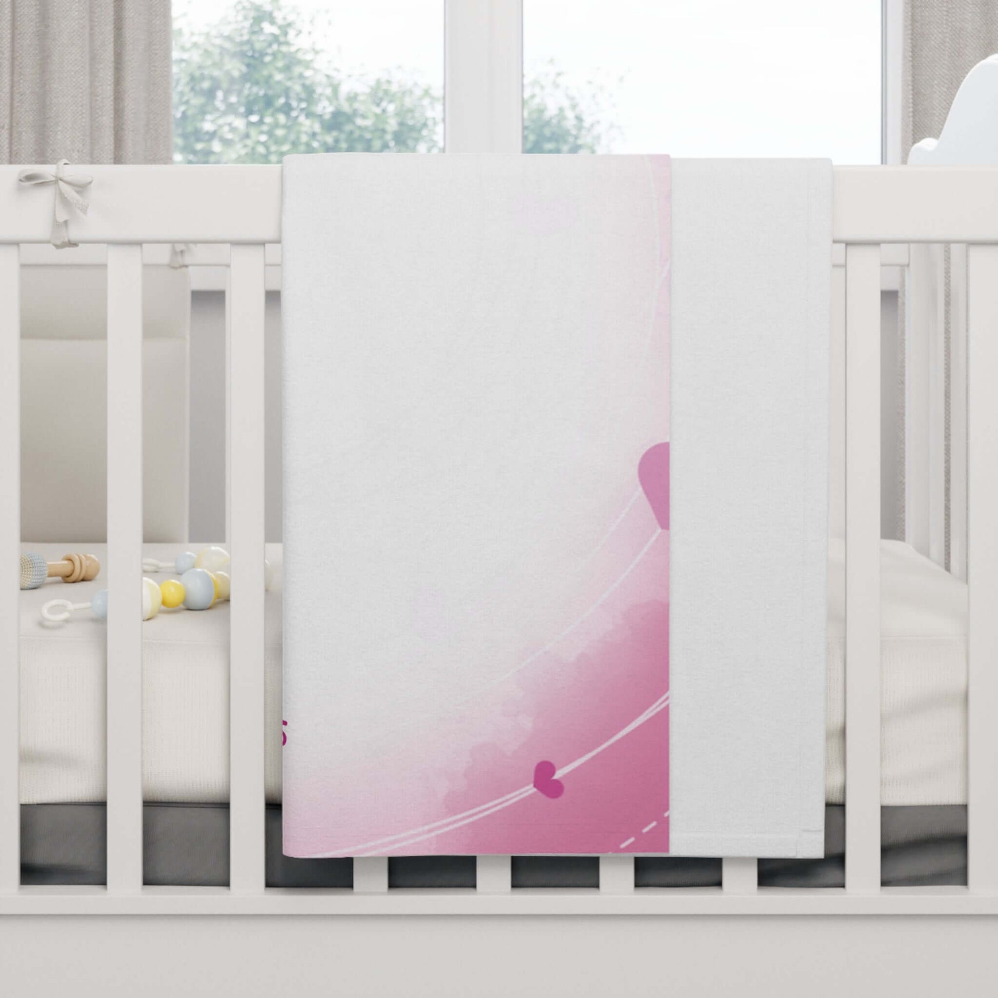 Personalized baby blanket with pink heart-themed design draped over a crib, perfect for nursery decor.