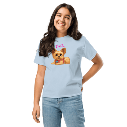 Smiling girl wearing a light blue shirt with a cartoon dog illustration and the name 'Stella' printed on it.