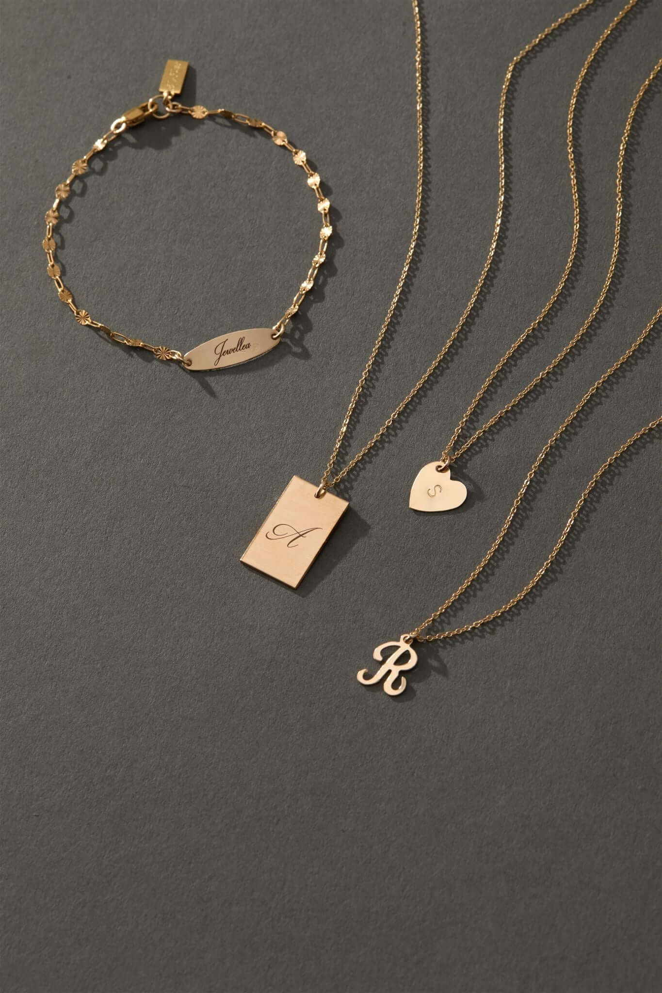 Stella Gold Initial Necklace – Personalized 14k Gold-Filled Pendant displayed with matching jewelry on a gray backdrop.