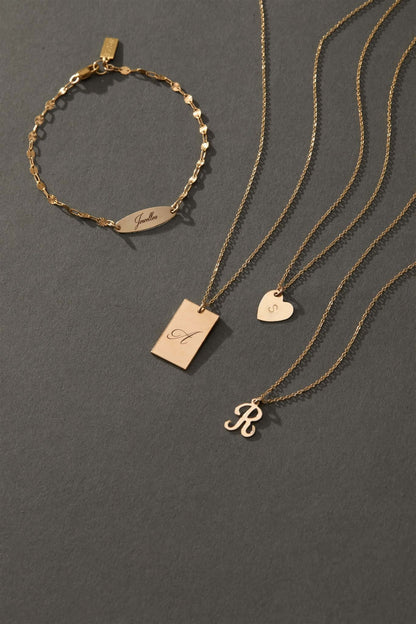 Stella Gold Initial Necklace – Personalized 14k Gold-Filled Pendant displayed with matching jewelry on a gray backdrop.
