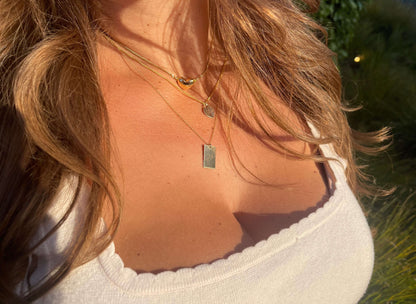Stella Gold Initial Necklace – Personalized 14k Gold-Filled Pendant worn by a woman, showcasing delicate layers in sunlight.