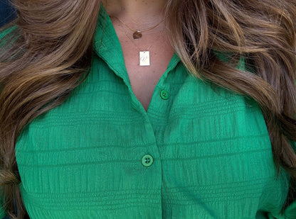 Stella Gold Initial Necklace – Personalized 14k Gold-Filled Pendant worn with a green button-up shirt.