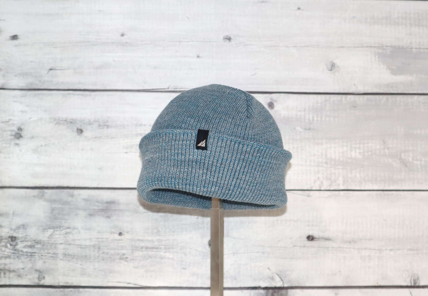 Toddler Acrylic Cuff Hat – Soft Knit Beanie displayed on a stand against a wood background.