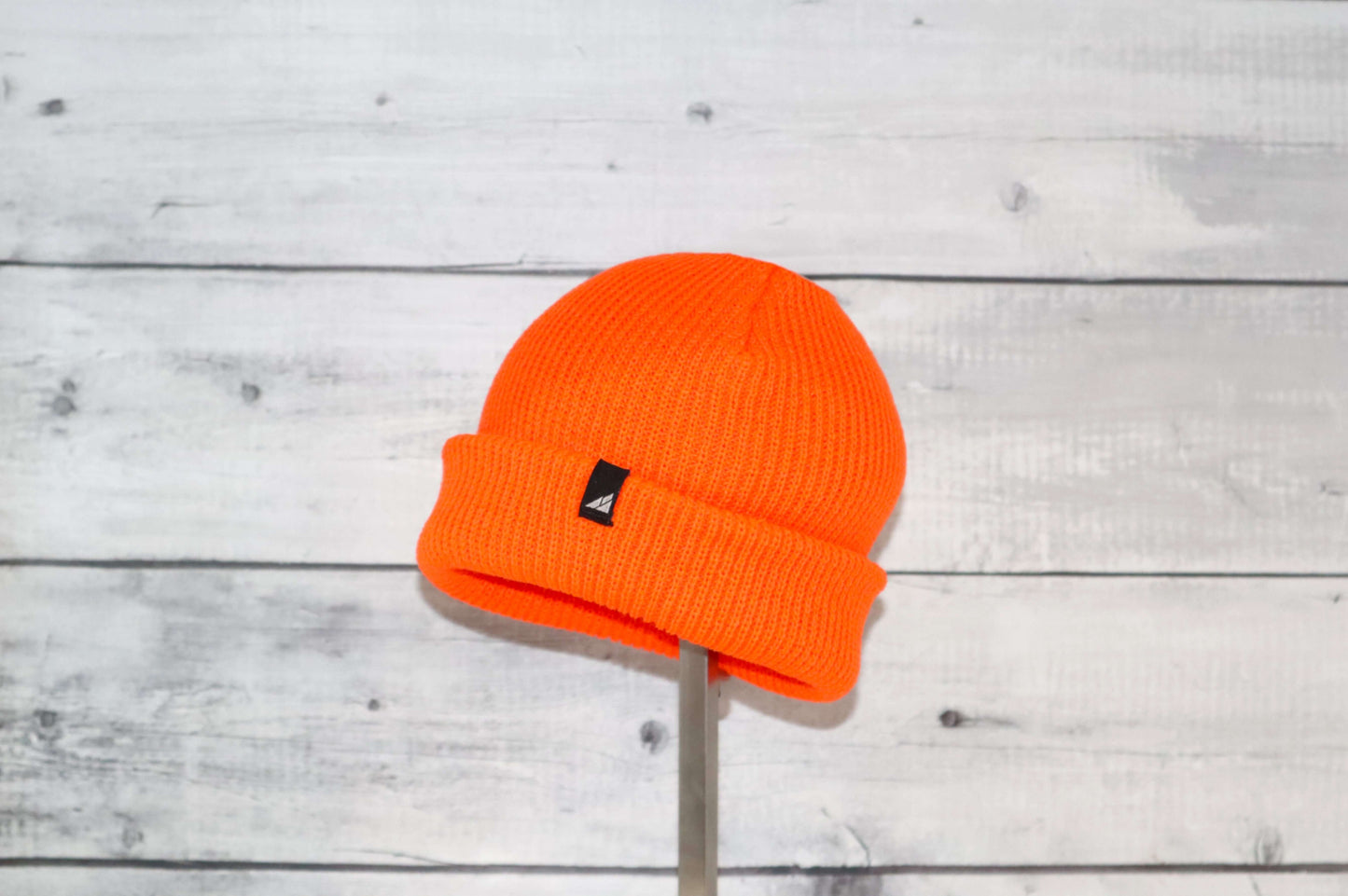 Toddler Acrylic Cuff Hat – Soft Knit Beanie in bright orange color on a wooden background.