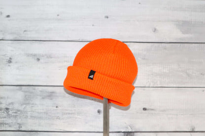 Toddler Acrylic Cuff Hat – Soft Knit Beanie in bright orange color on a wooden background.