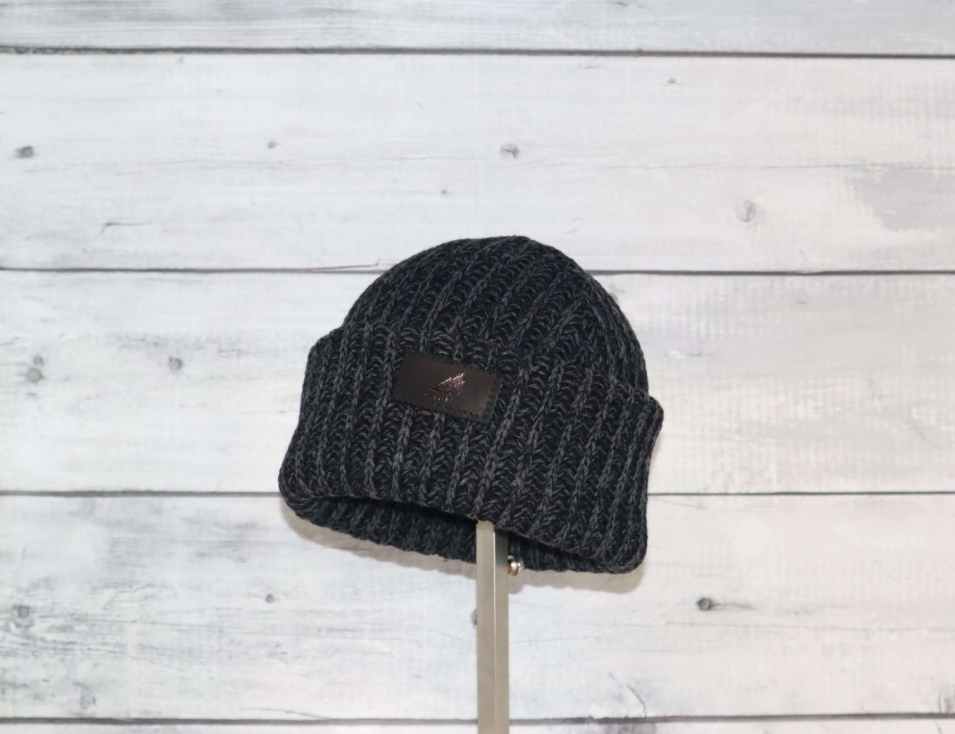 Toddler Acrylic Ribbed Cuff Hat – Soft, Stretchy & Made to Give displayed on a stand against a rustic wooden background.