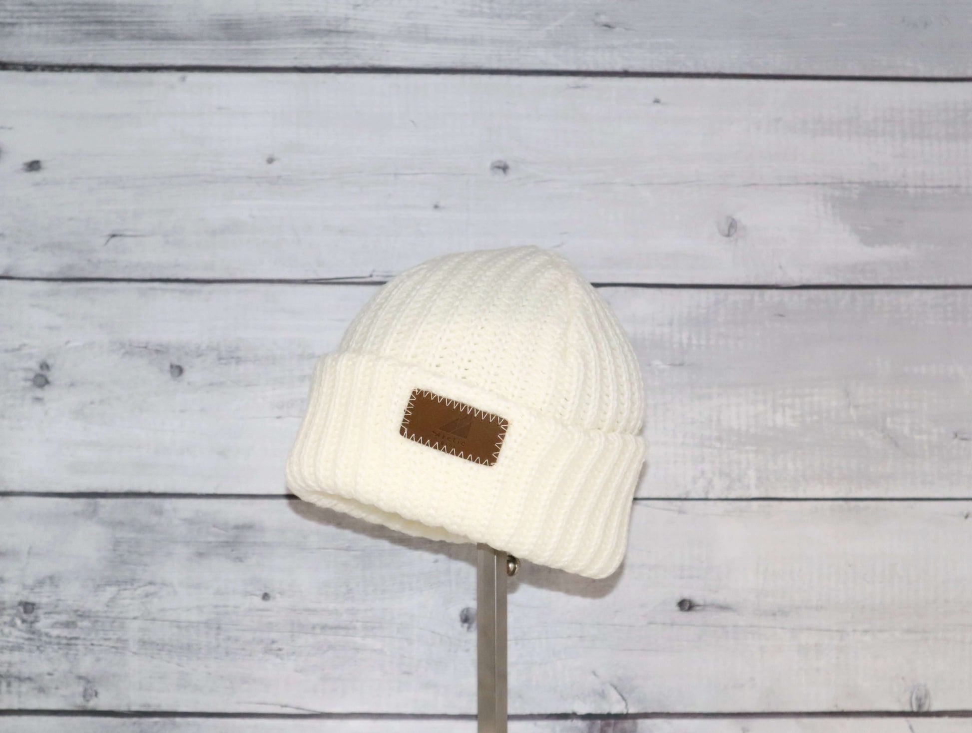 Toddler Acrylic Ribbed Cuff Hat – Soft, Stretchy & Made to Give displayed on a stand against a rustic wood background.
