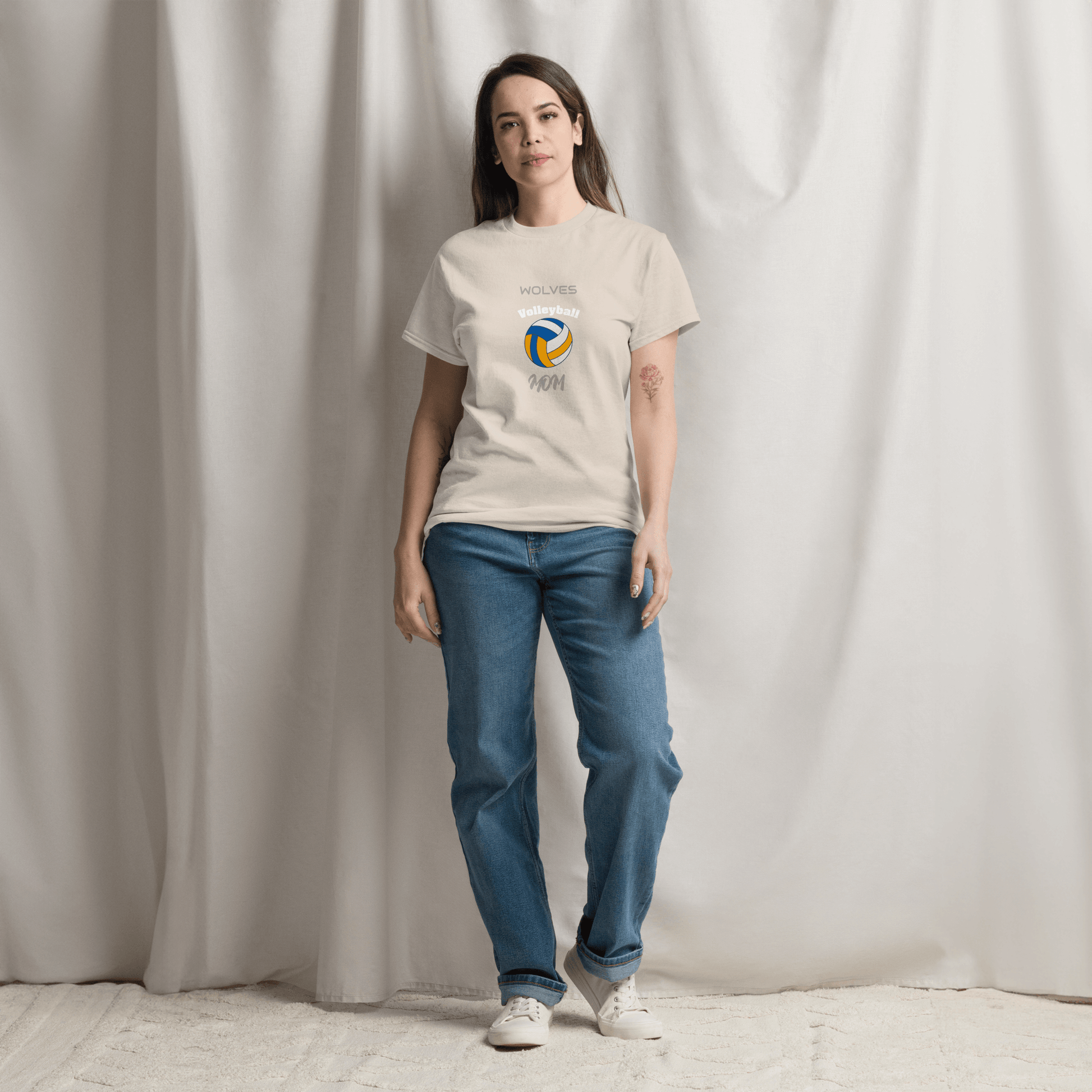 Woman wearing a beige volleyball parent tee featuring 'Wolves' design, perfect for game day support.