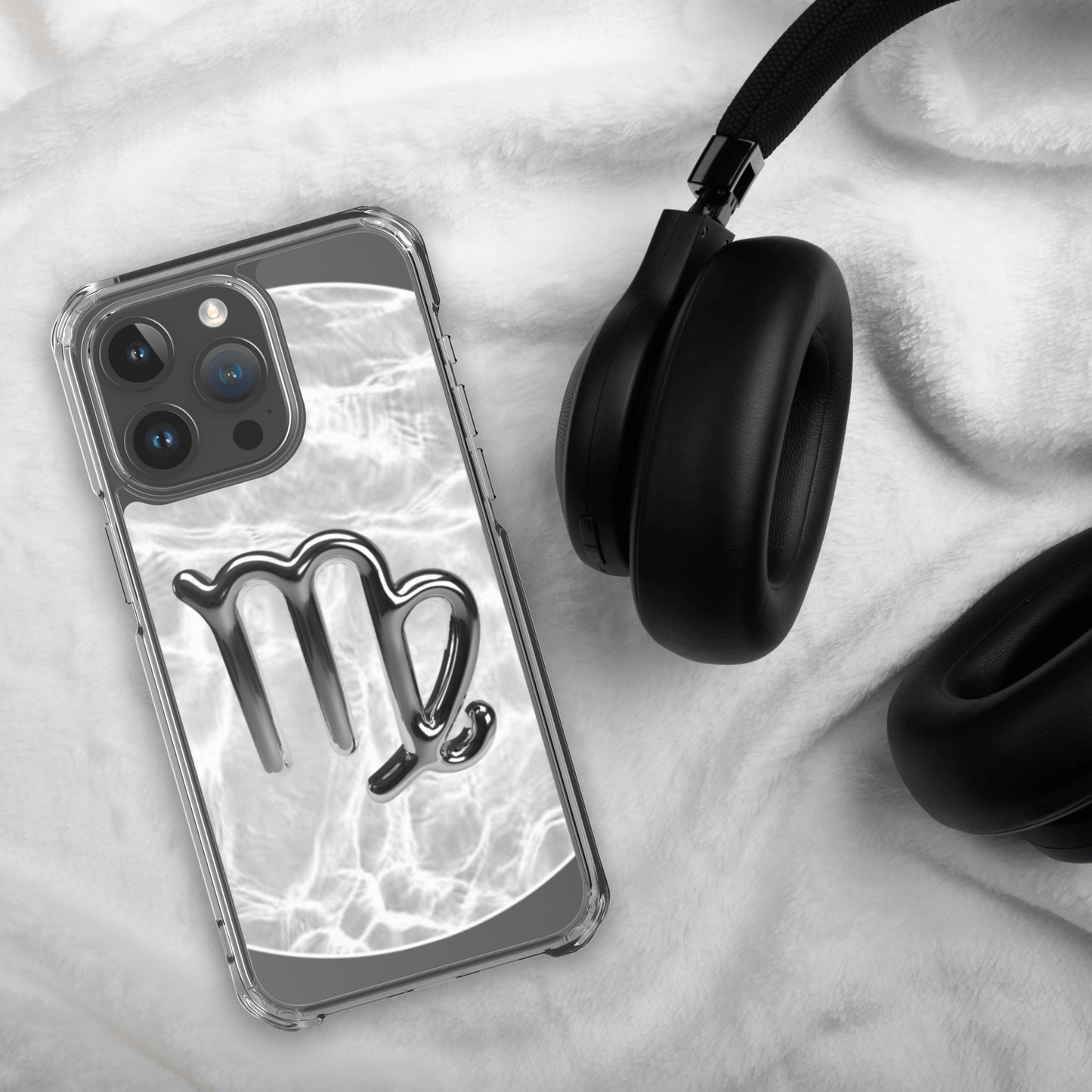 Zodiac Virgo Magsafe clear iPhone case with metallic design next to black headphones on furry surface.