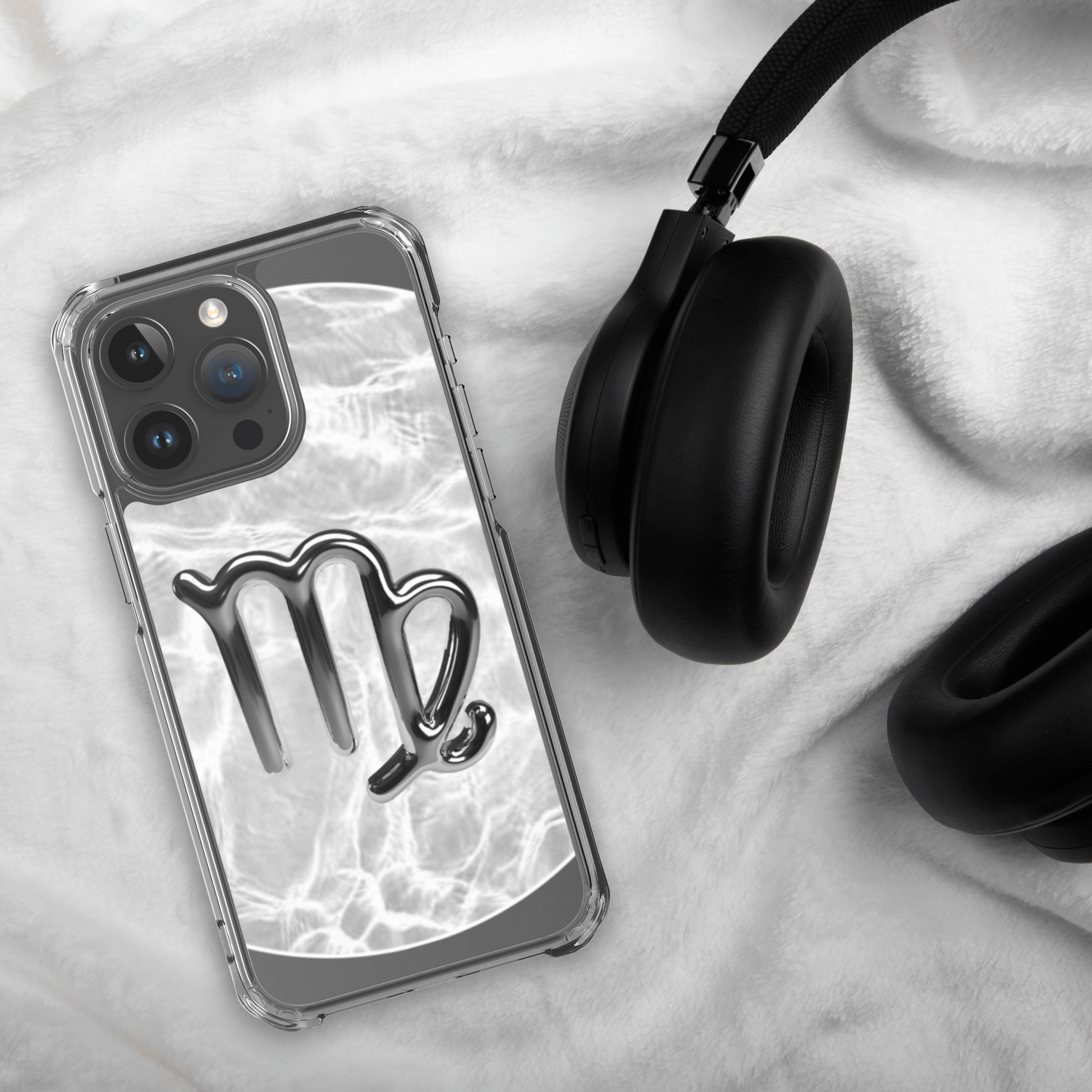 Zodiac Virgo Magsafe clear iPhone case with metallic design next to black headphones on furry surface.