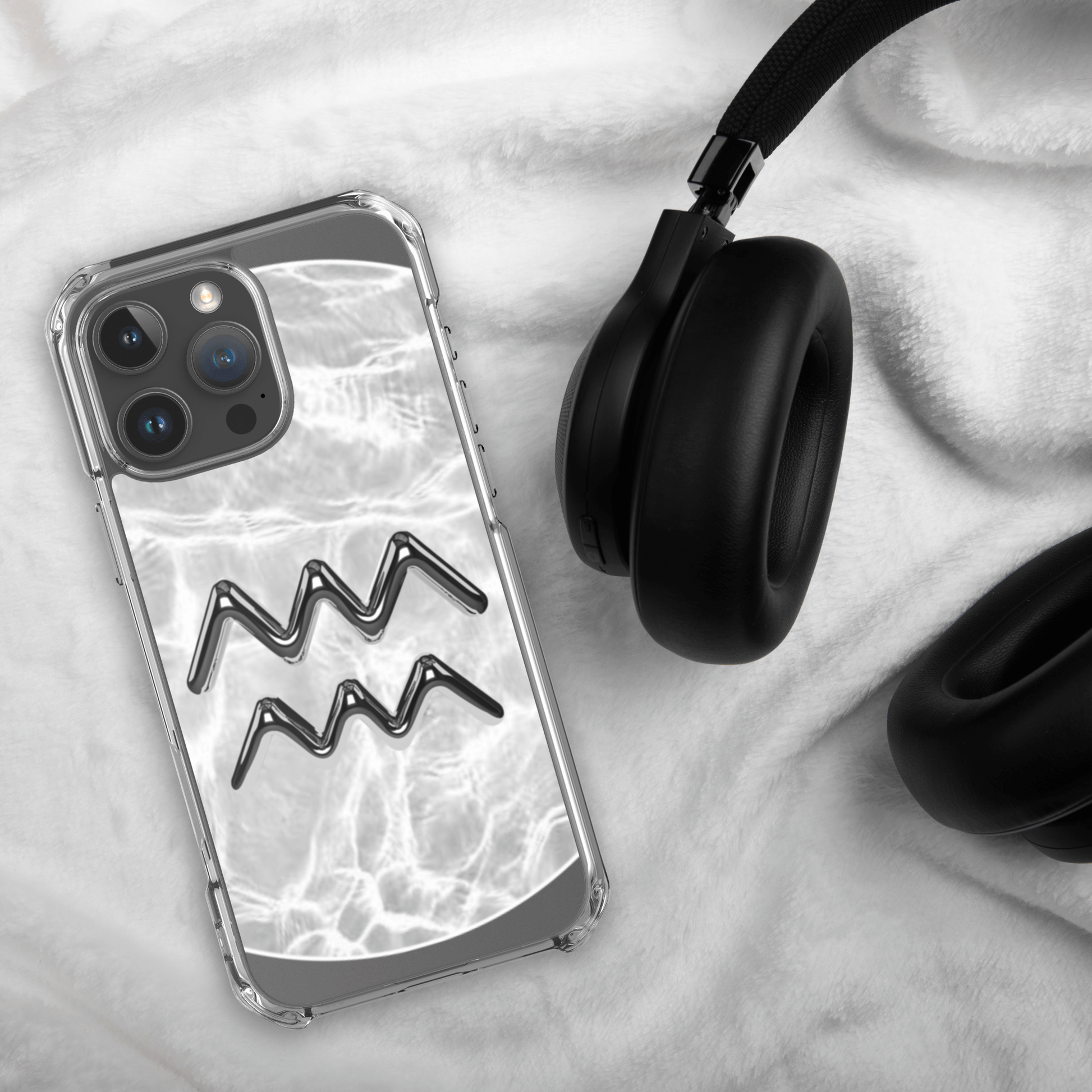 Zodiac Aquarius clear iPhone case with marble design next to black headphones on a soft fabric background.