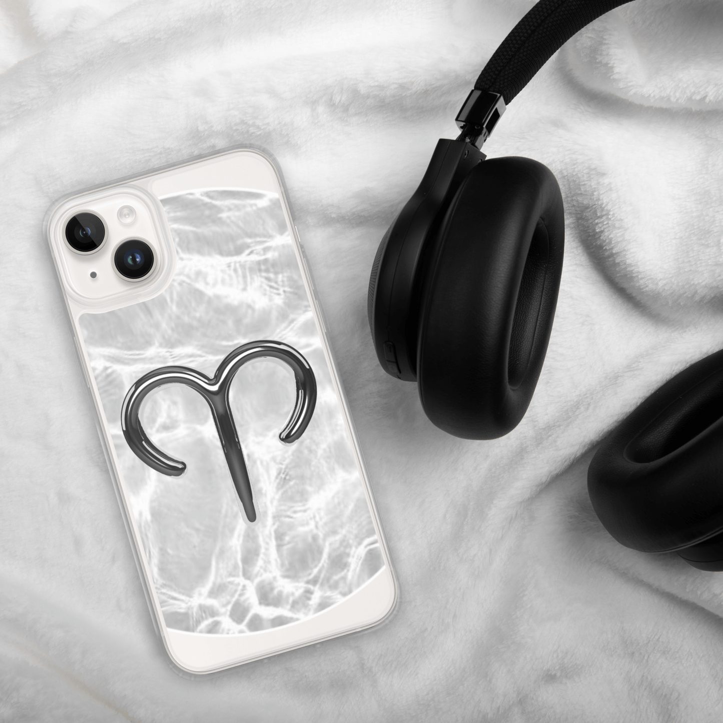 Zodiac Aries MagSafe clear iPhone case with marble design on soft surface next to black headphones.
