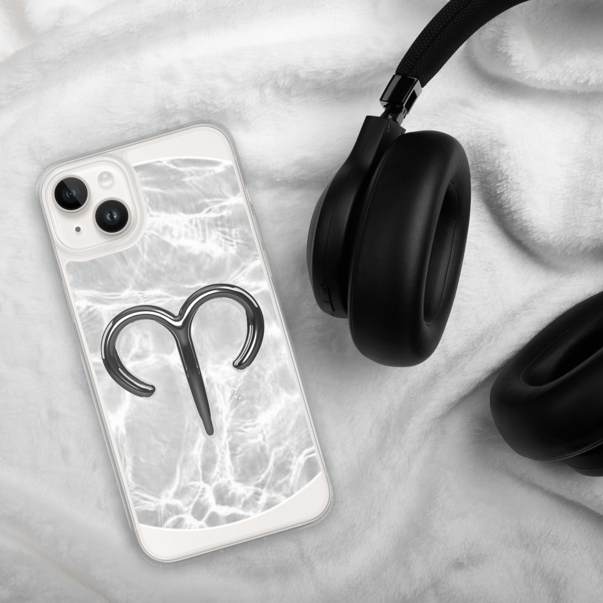 Zodiac Aries MagSafe clear iPhone case with marble design on soft surface next to black headphones.