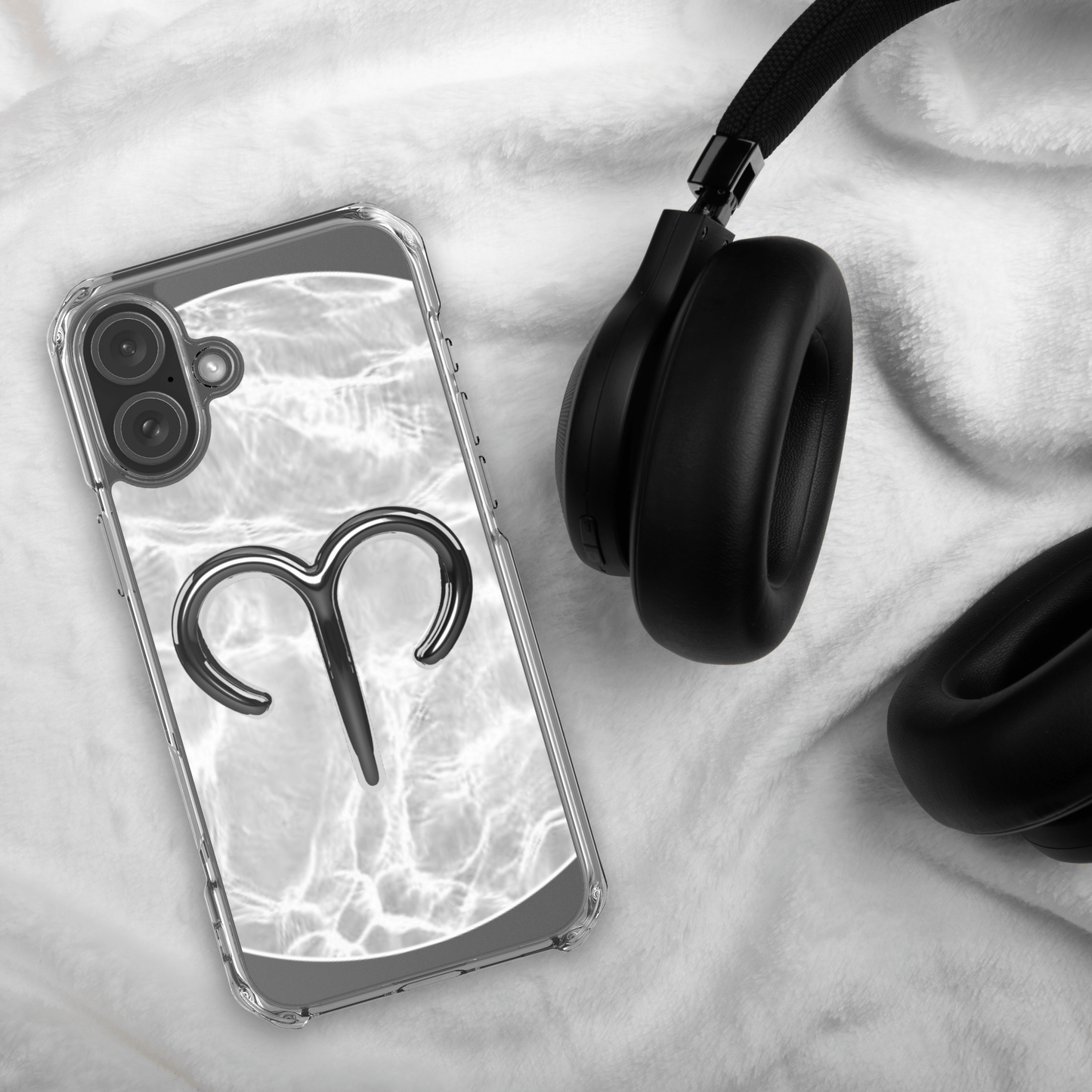 Zodiac Aries MagSafe clear iPhone case with metallic design on marble background next to black headphones.