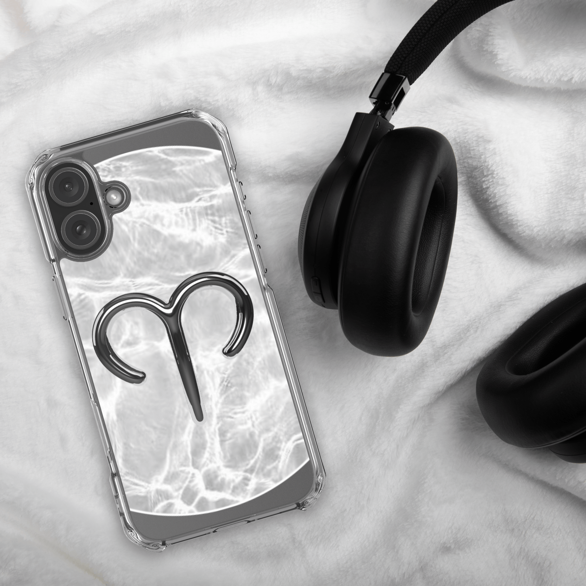 Zodiac Aries MagSafe clear iPhone case with metallic design on marble background next to black headphones.