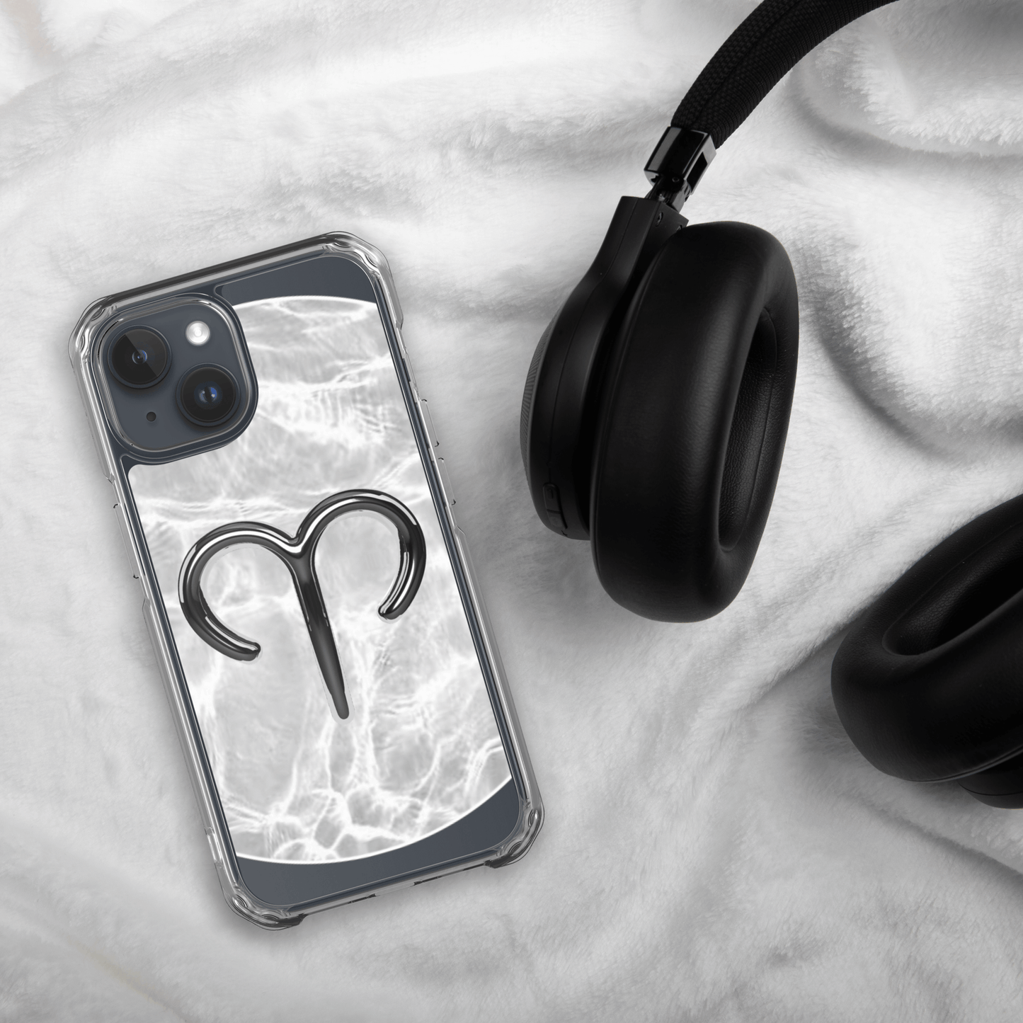Zodiac Aries MagSafe clear iPhone case with metallic design on marble background next to black headphones.