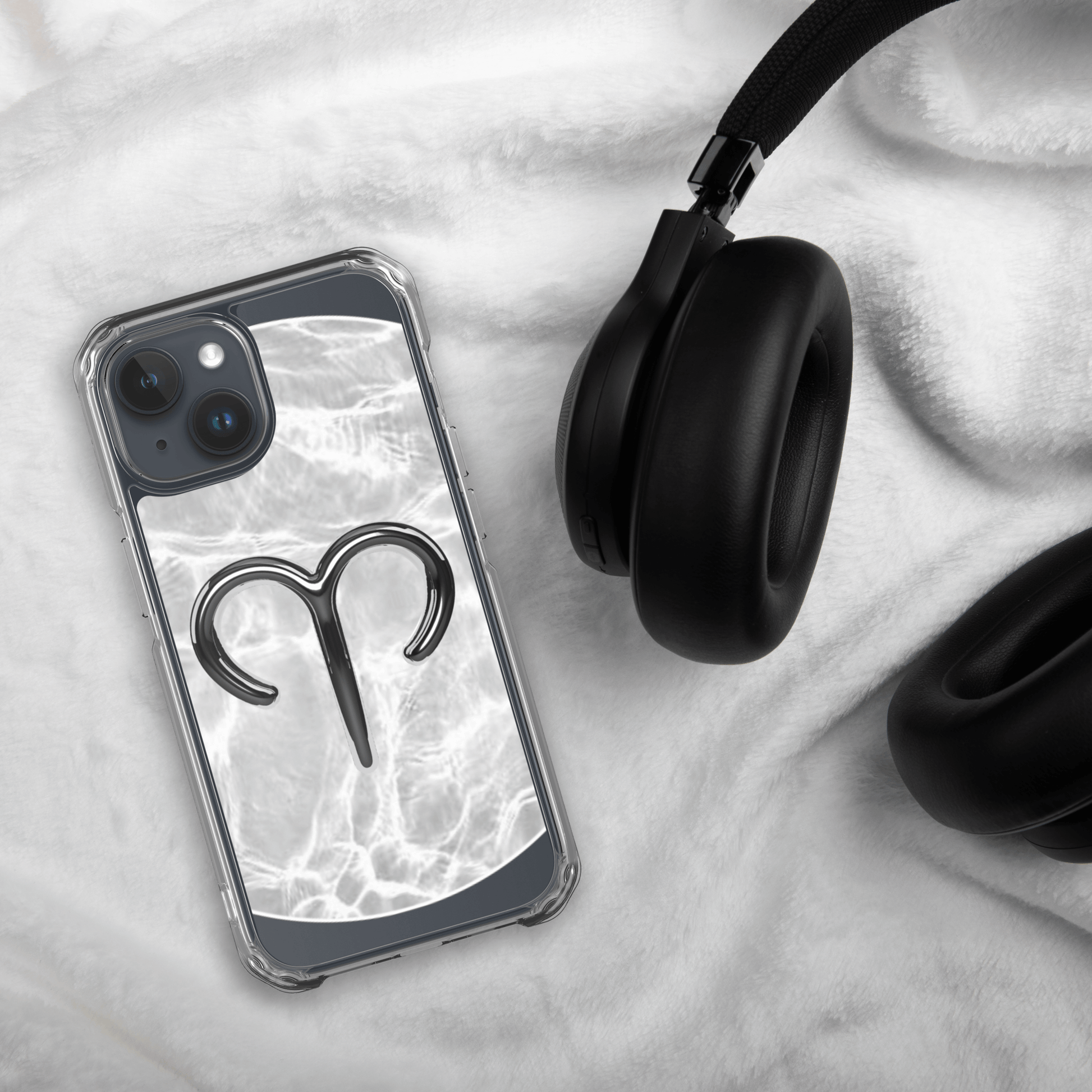 Zodiac Aries MagSafe clear iPhone case with metallic design on marble background next to black headphones.