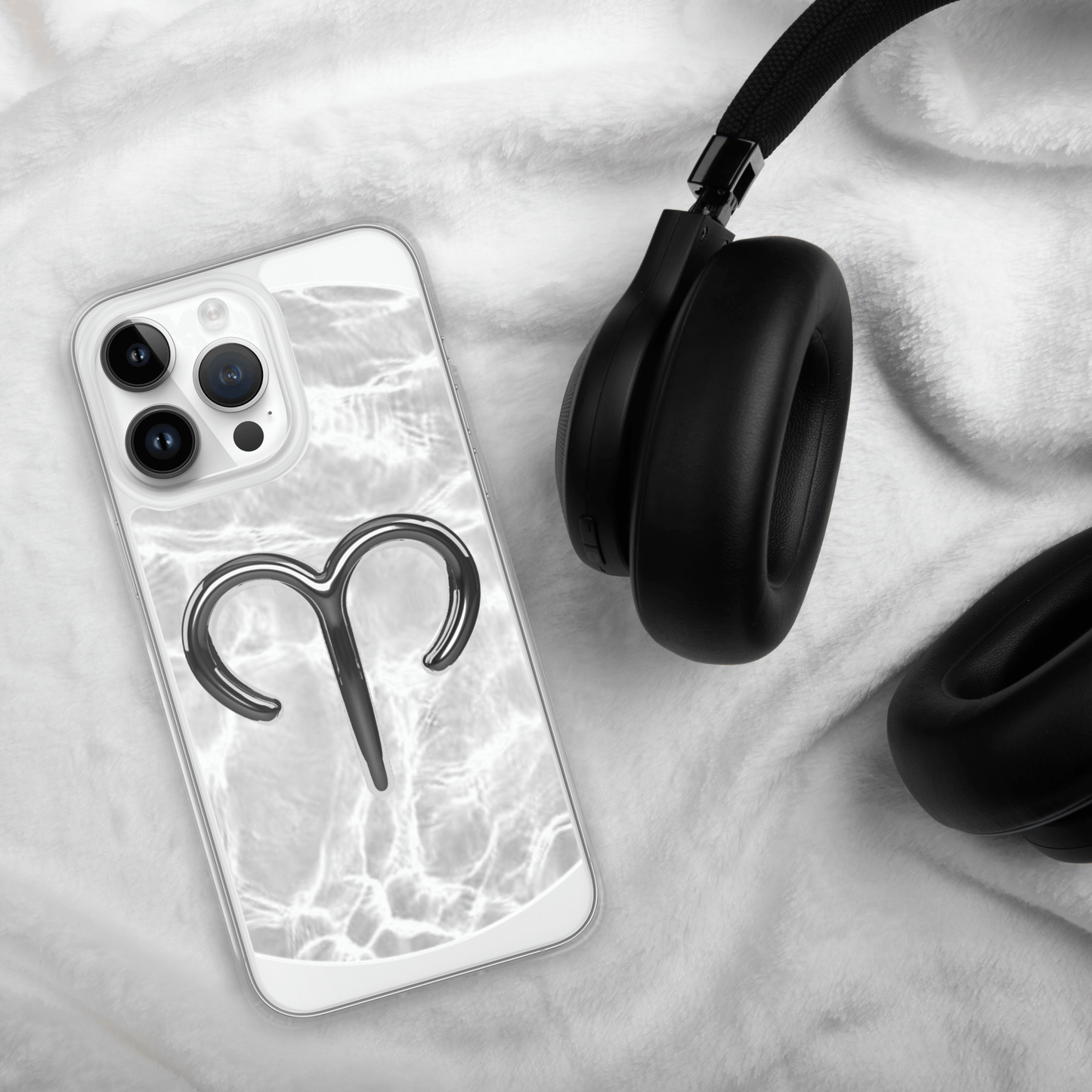 Zodiac Aries MagSafe clear iPhone case with metallic design on marble background next to headphones.