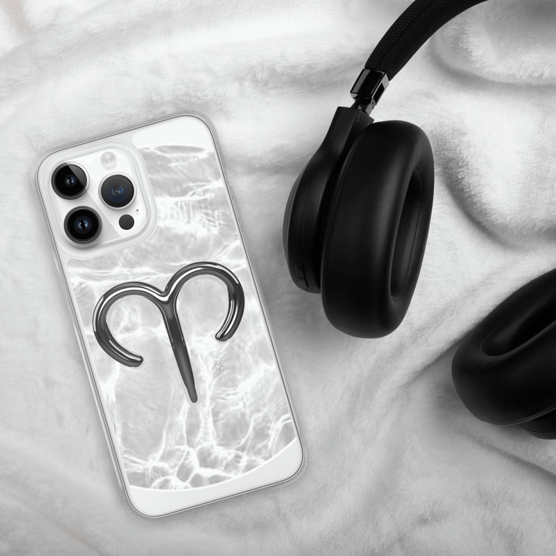 Zodiac Aries MagSafe clear iPhone case with metallic design on marble background next to headphones.