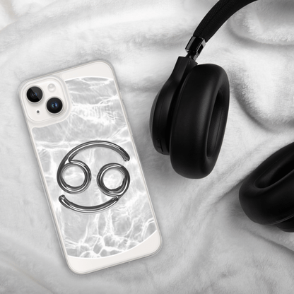 Zodiac Cancer MagSafe clear iPhone case with metallic design on soft backdrop next to black headphones.