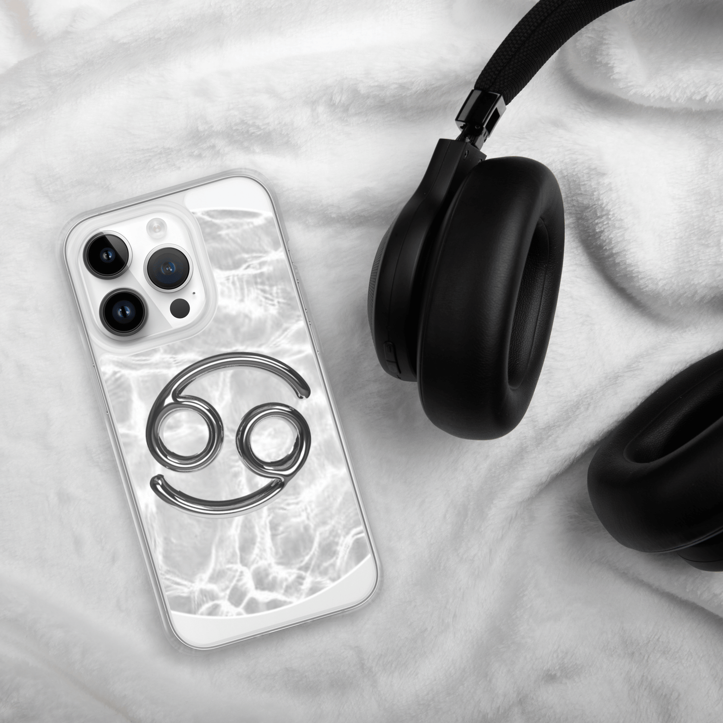 Zodiac Cancer Magsafe Clear iPhone Case with metallic design on cozy background next to headphones.