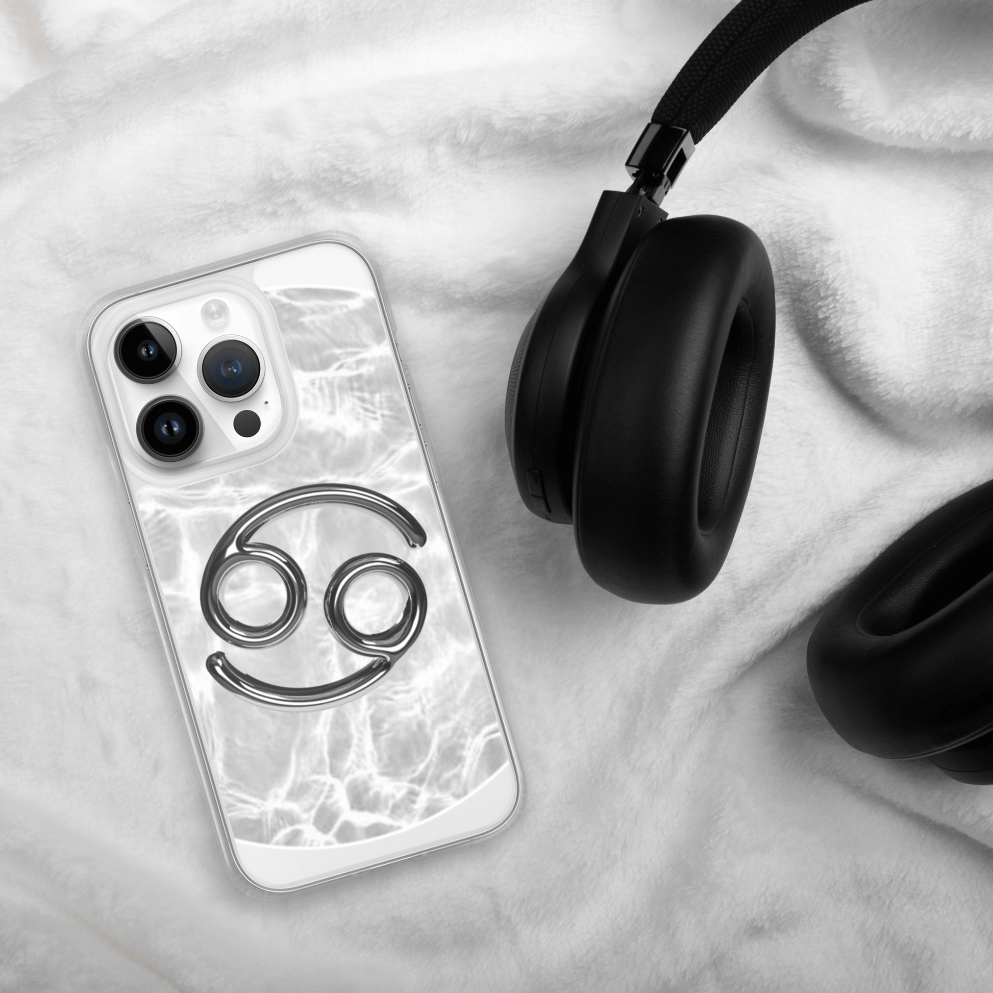 Zodiac Cancer Magsafe Clear iPhone Case with metallic design on cozy background next to headphones.